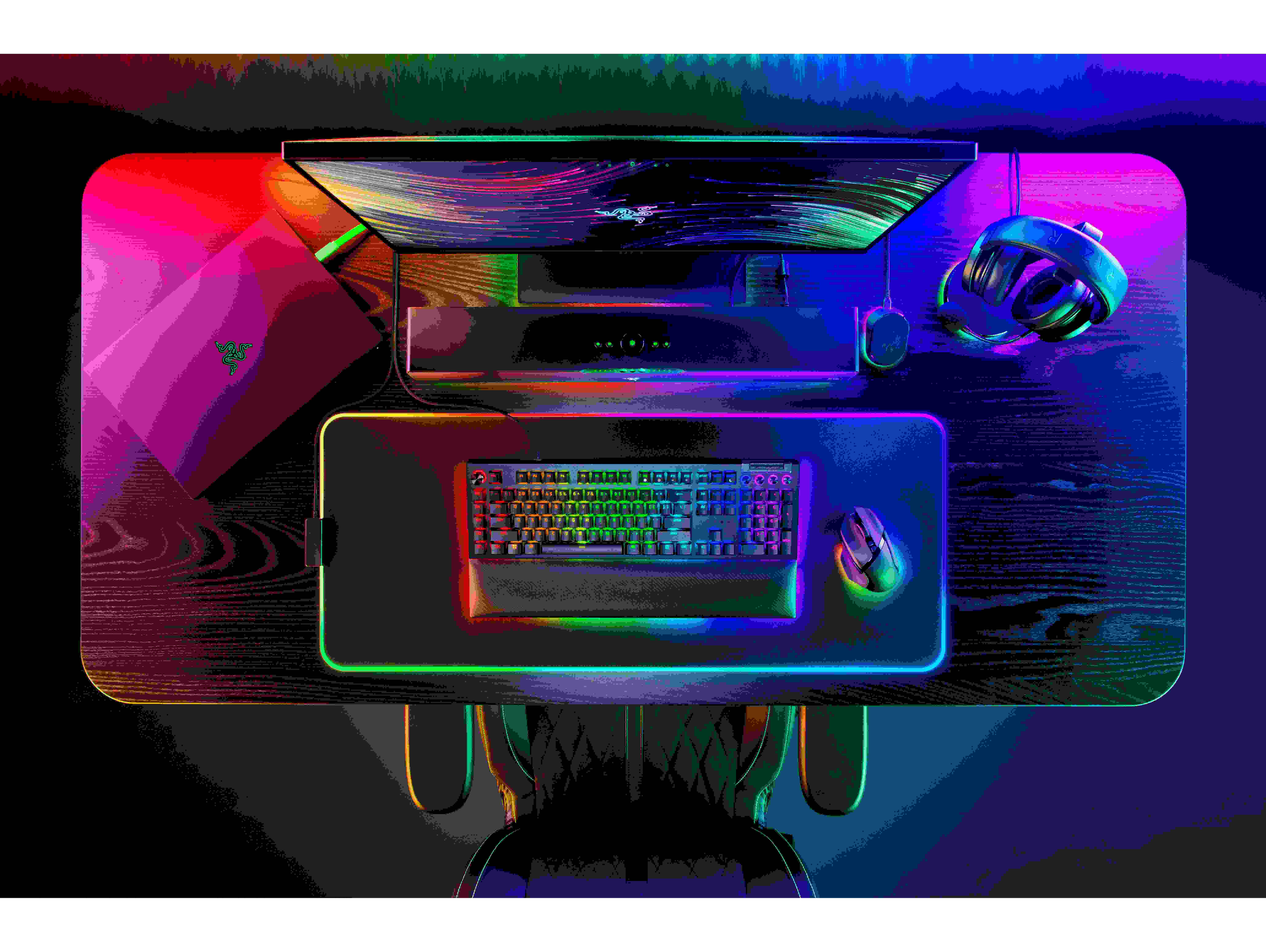 Vista dall'alto di una configurazione di gioco. Include monitor, tastiera, mouse e cuffie. Scuro, illuminato.