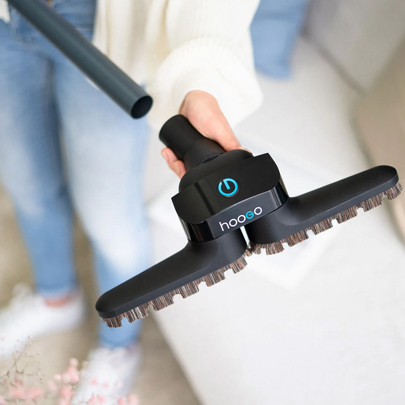 Eine Hand, die einen schwarzen Staubsaugeraufsatz mit Bürsten hält.