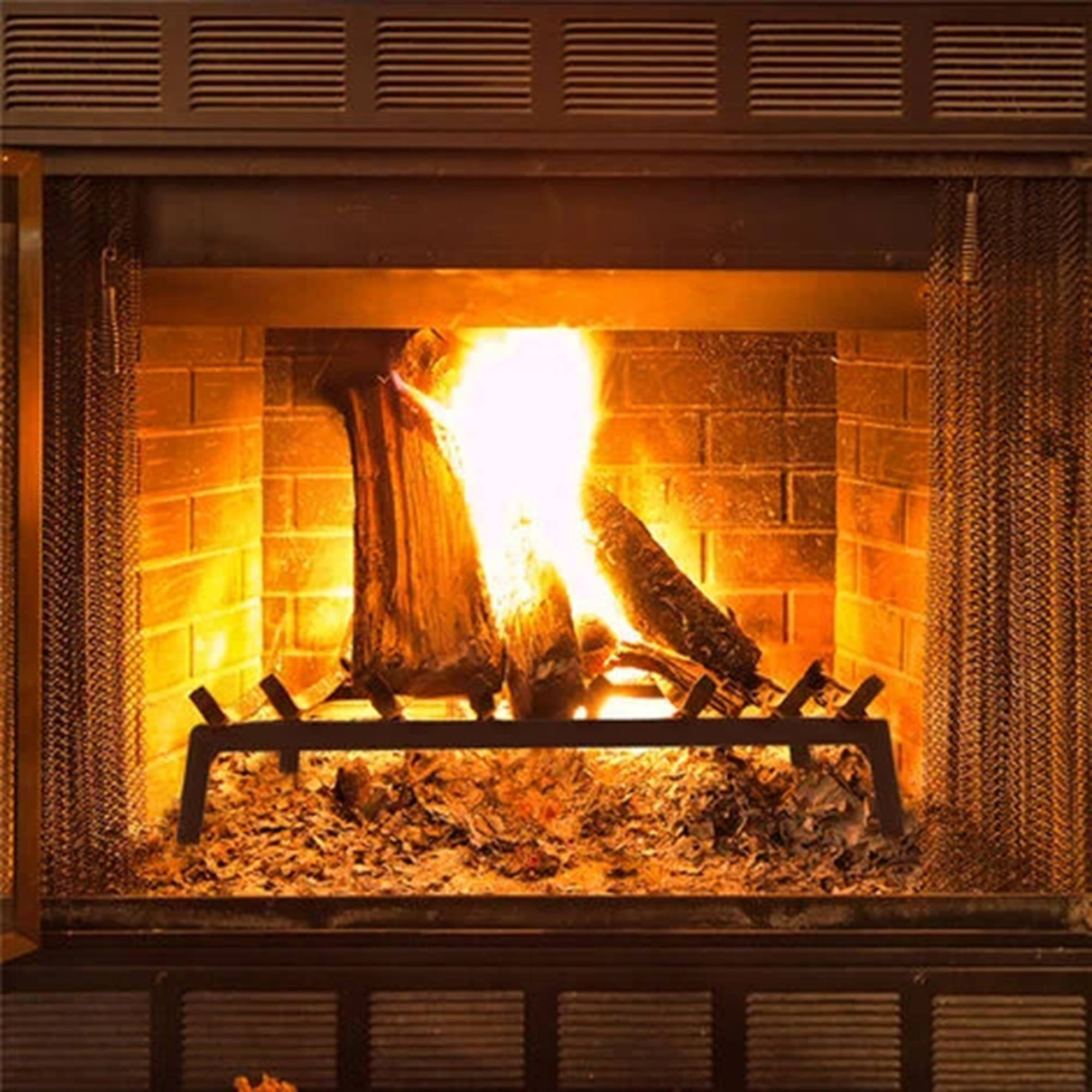 Una chimenea con leña ardiendo, brasas y un atizador. Fondo de pared de ladrillos.
