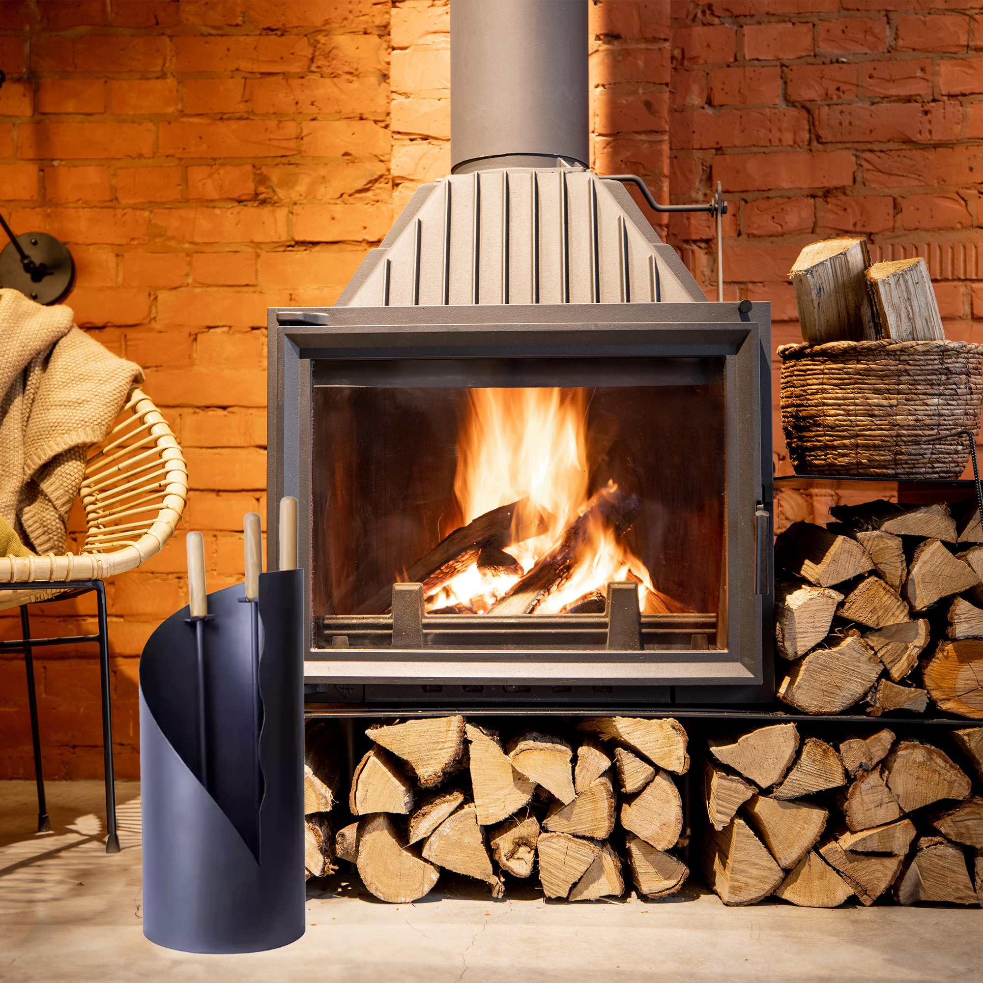 Una chimenea con fuego crepitante, leña apilada alrededor y una cesta tejida con leña.