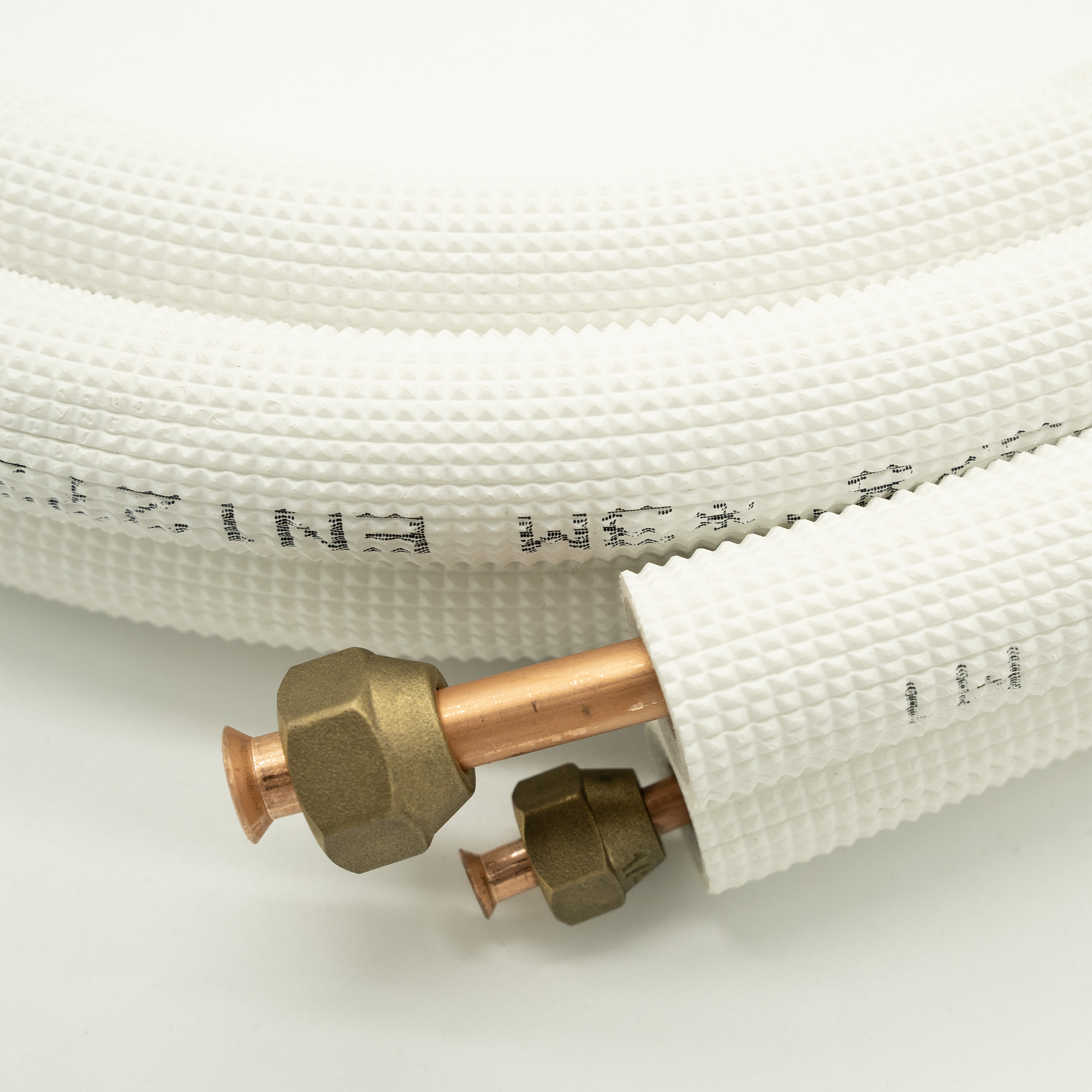 Close-up of white, insulated air conditioning pipes with copper fittings. White background.