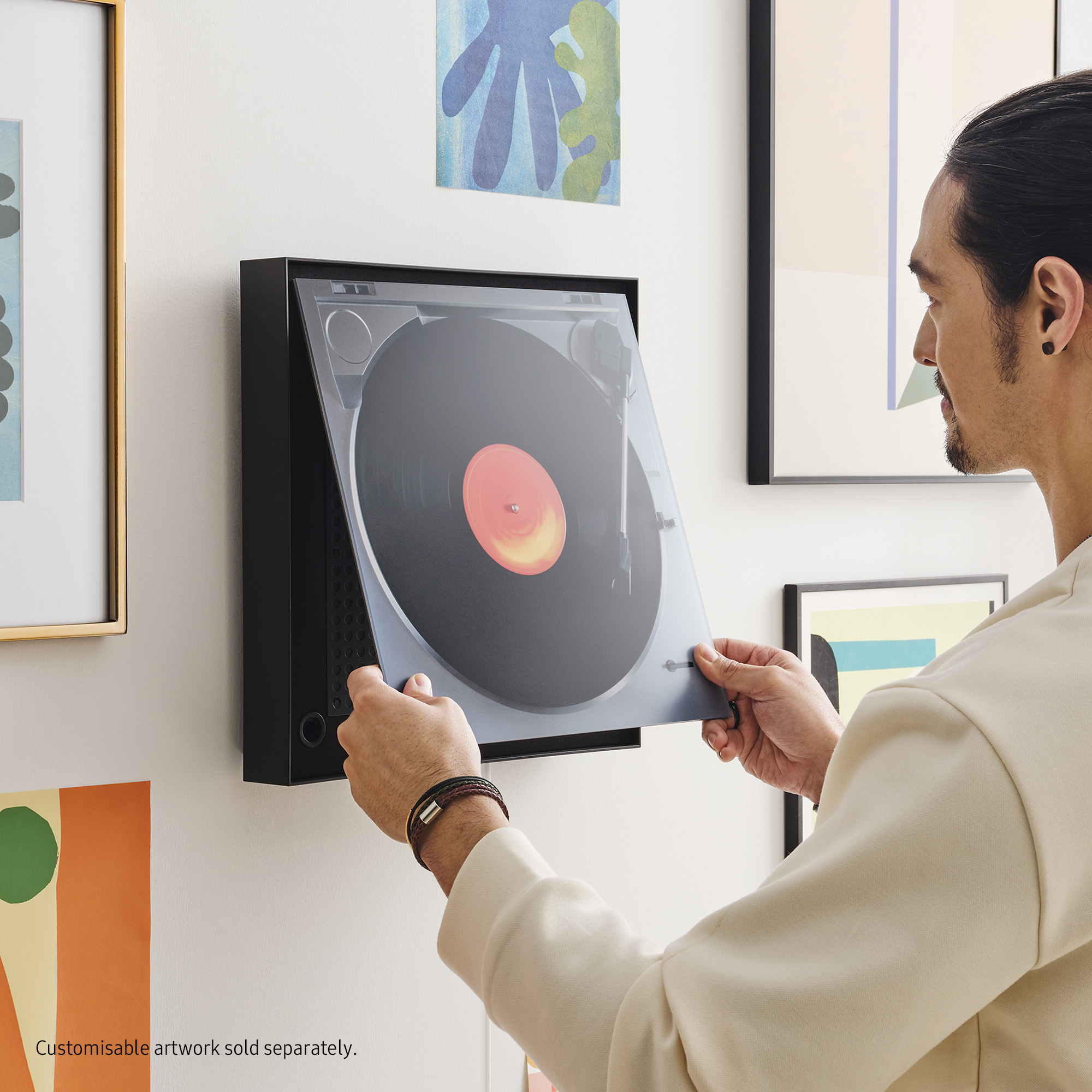 Mężczyzna instalujący płytę winylową w odtwarzaczu na ścianie.