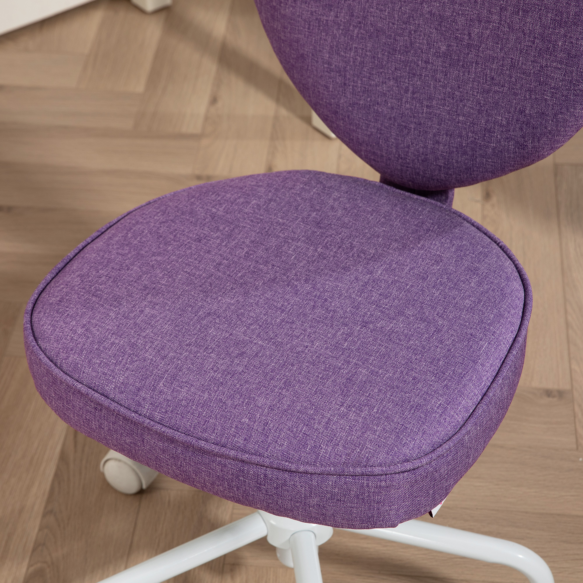 Primo piano della seduta di una sedia viola. Il tessuto è viola. La sedia è su una base bianca. Il pavimento è in legno.