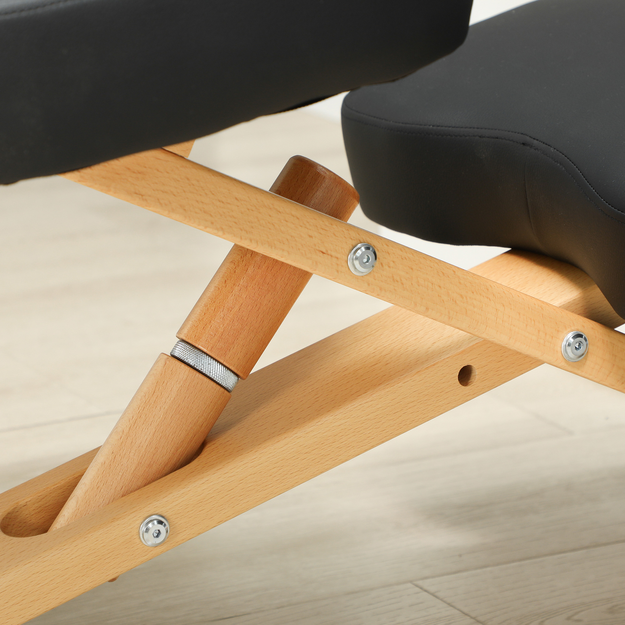 Dettaglio del tavolo da massaggio in legno, con cuscino nero e supporto in legno regolabile.