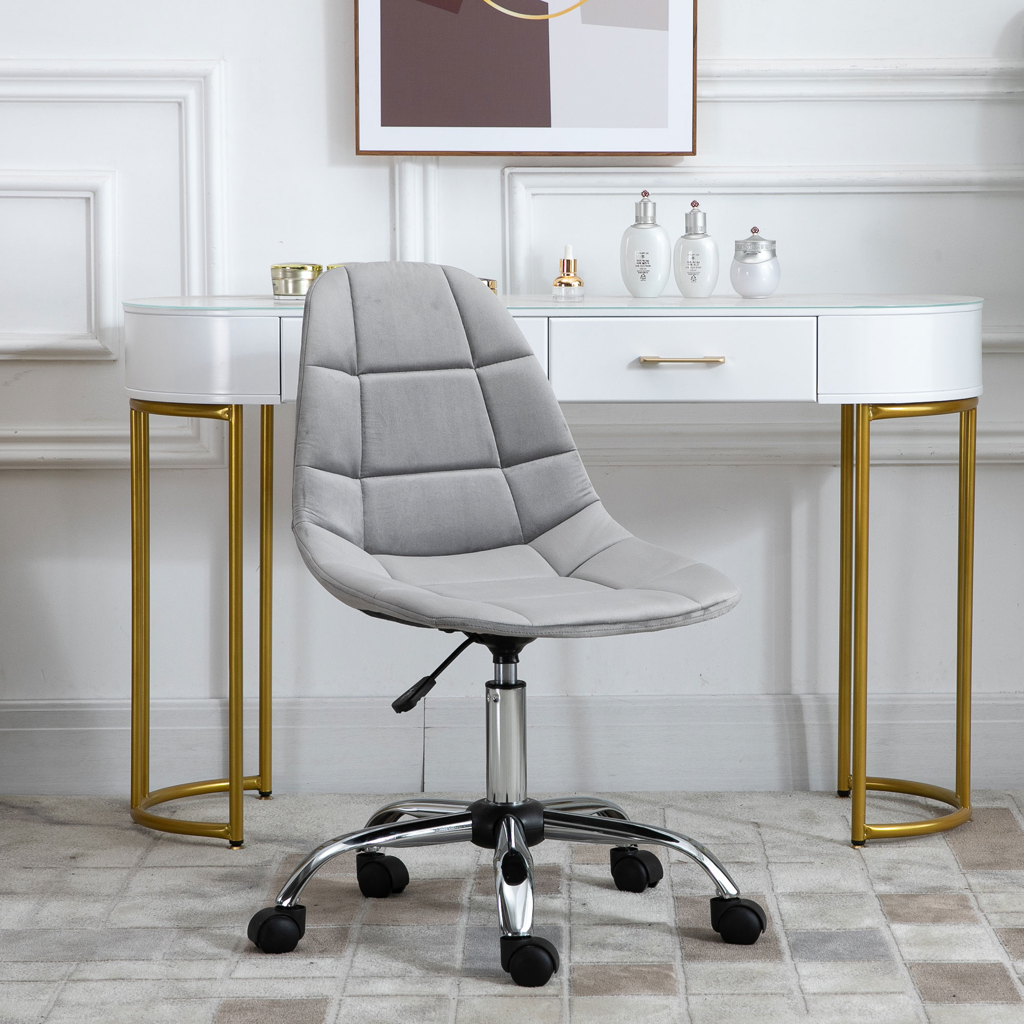 Sedia da ufficio in velluto grigio davanti a una scrivania bianca. Accessori e un'immagine sopra.