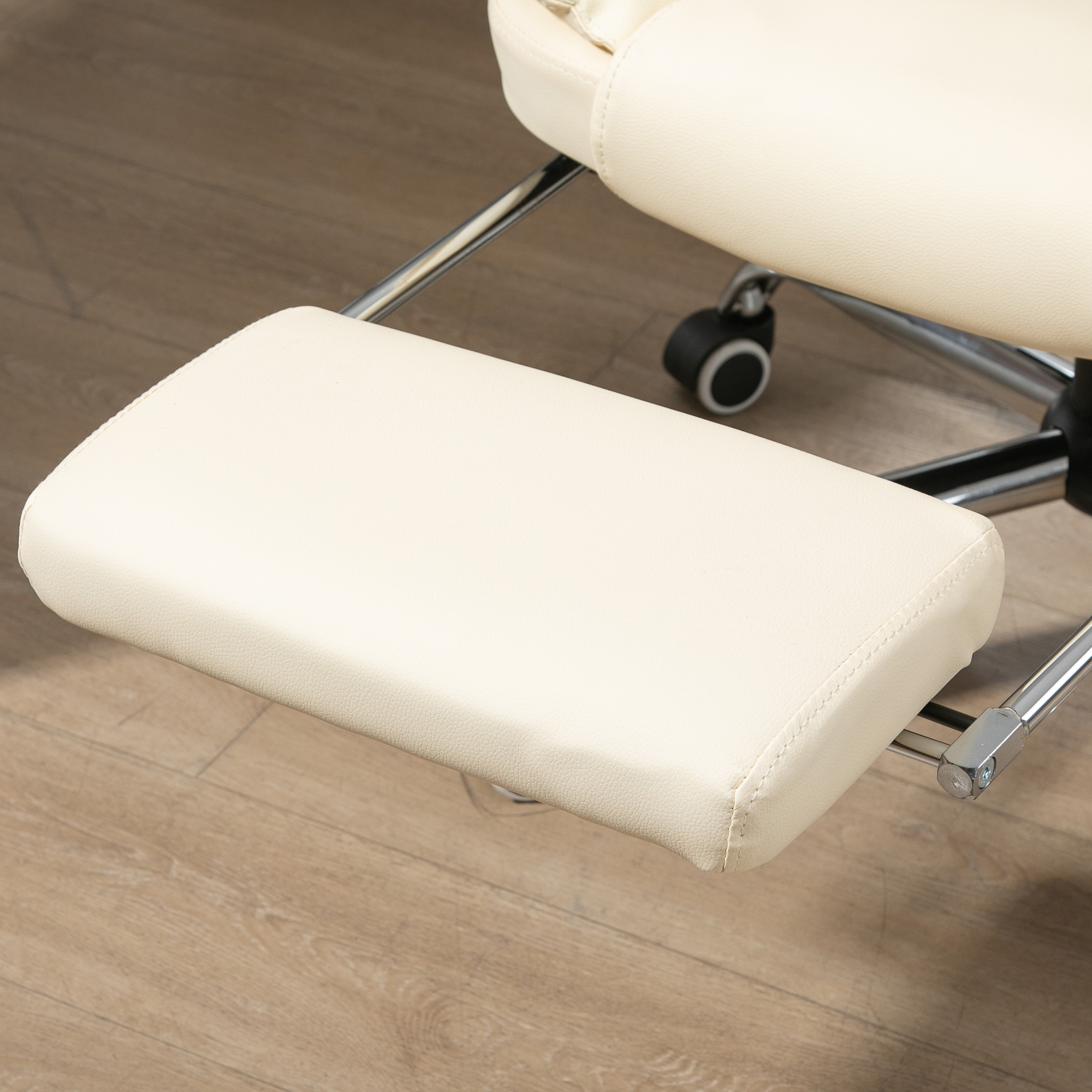 Poggiapiedi color crema attaccato a una sedia da ufficio con base cromata. Pavimento in legno.