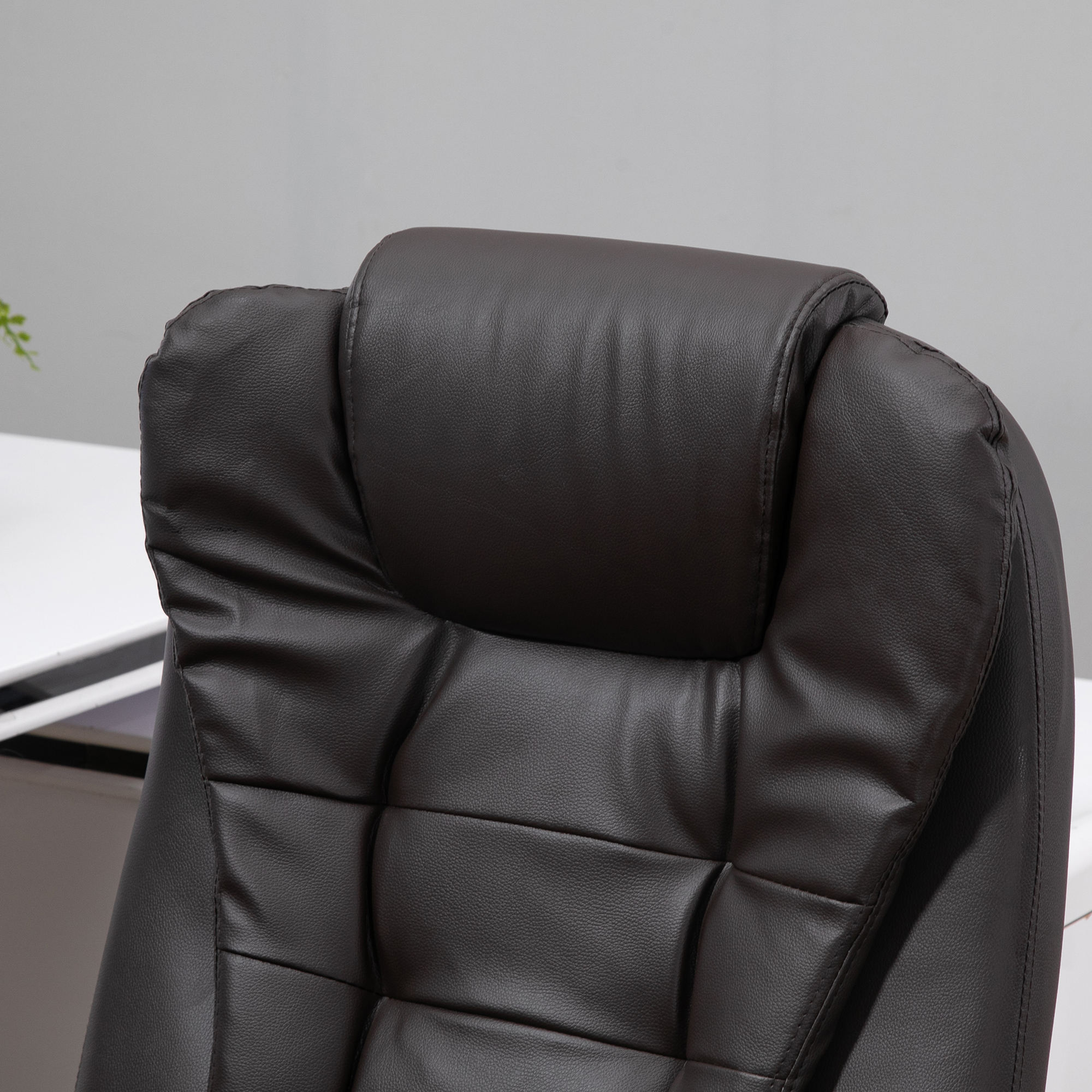 Brauner Bürostuhl aus Leder mit Kopfstütze und Schreibtisch im Hintergrund.