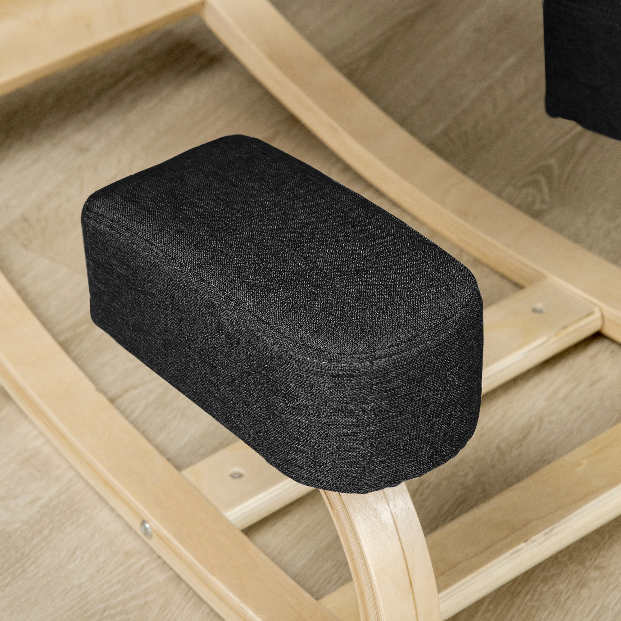 Una seduta imbottita nera di una sedia a ginocchia in legno.
