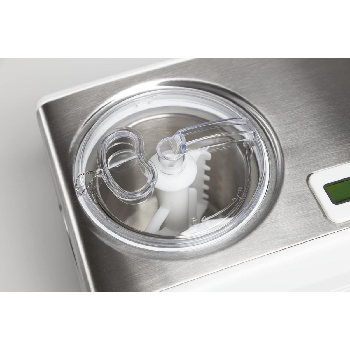Widok z góry na maszynę do lodów, przezroczysta pokrywa, białe mieszadło i srebrny metalowy korpus.