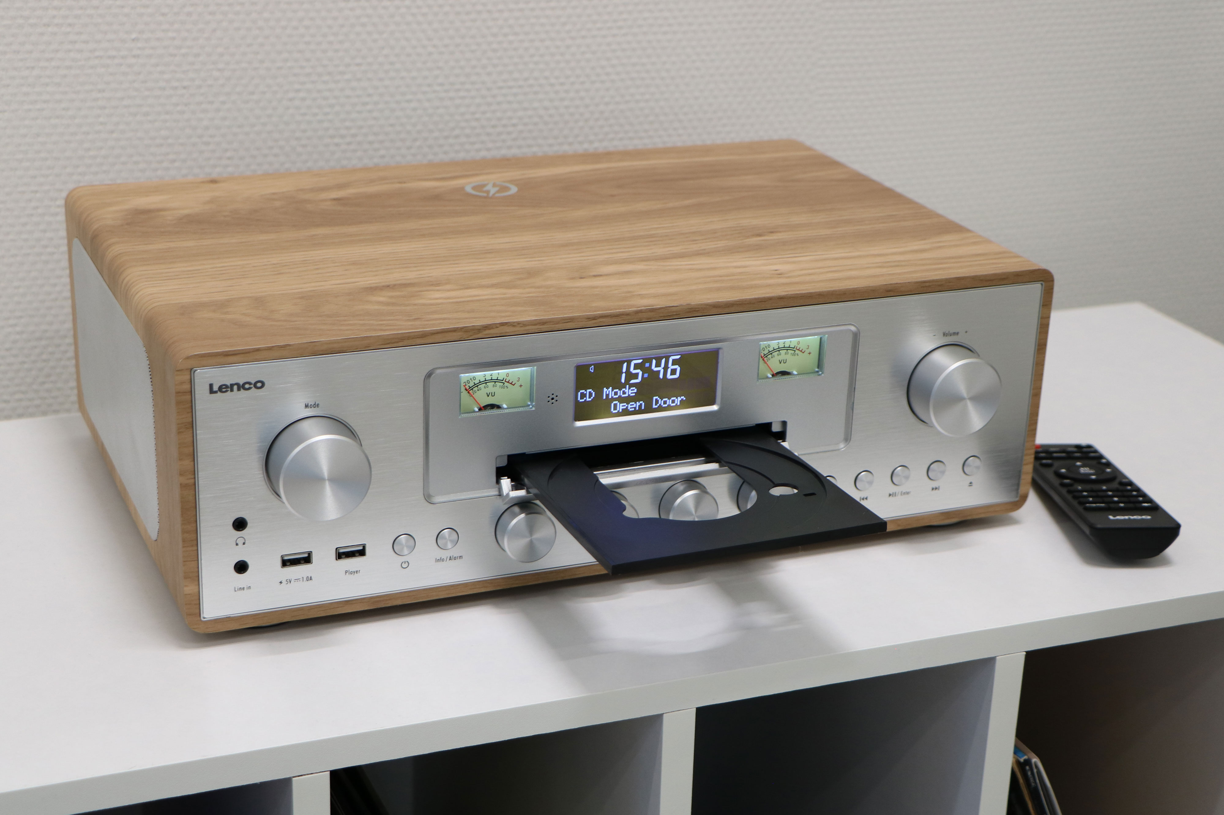 Een vintage houten radio met cd-speler en afstandsbediening op een witte plank.
