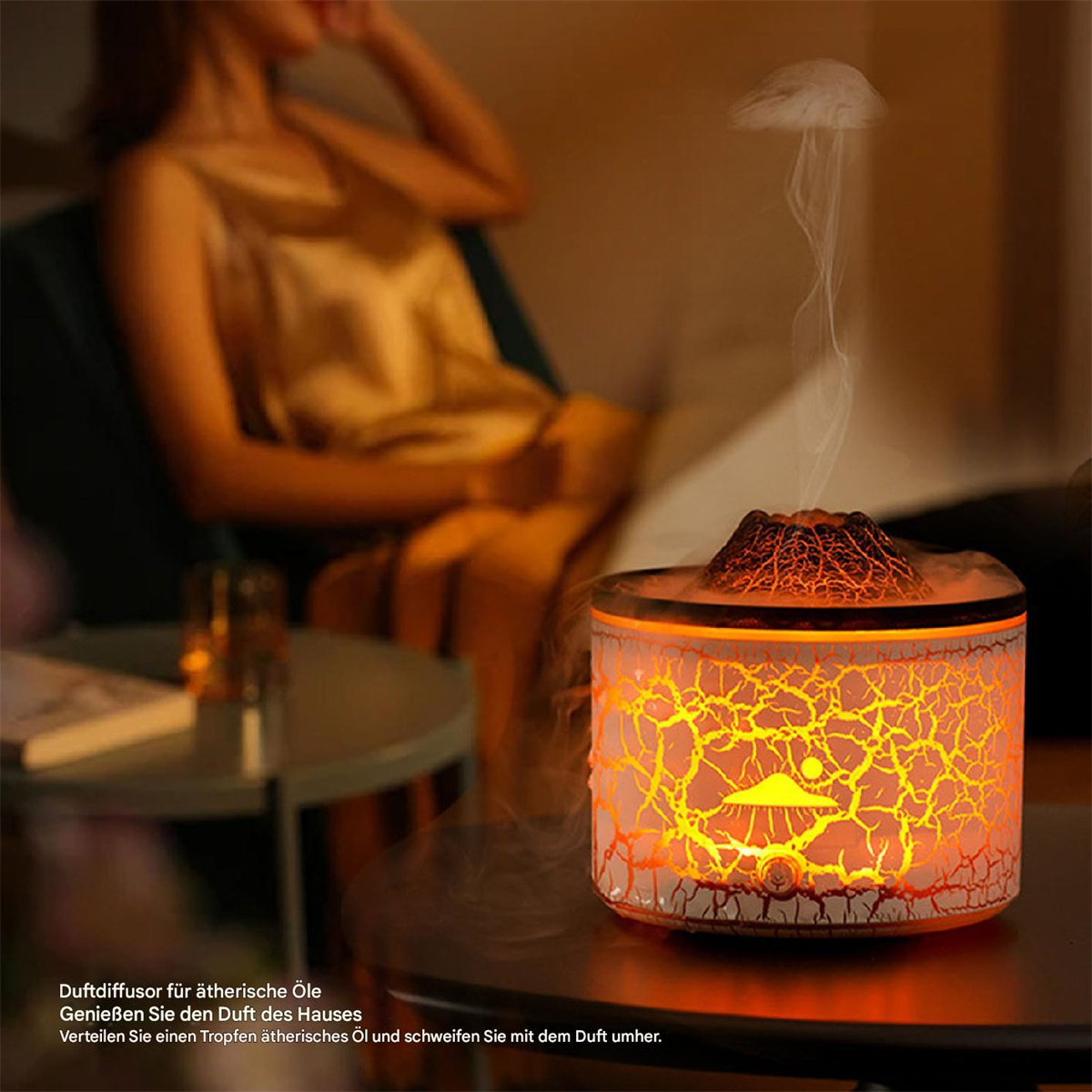 Ein beleuchteter Aromatherapie-Diffusor mit Vulkan-Design und eine Frau im Hintergrund.