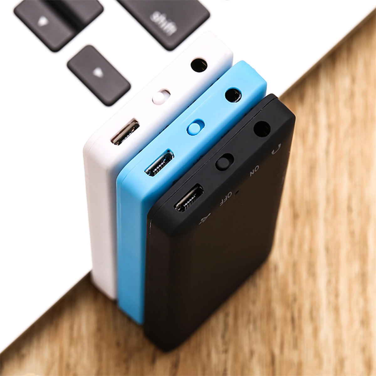 Drei kleine, farbige USB-Laufwerke auf einer Tastatur.