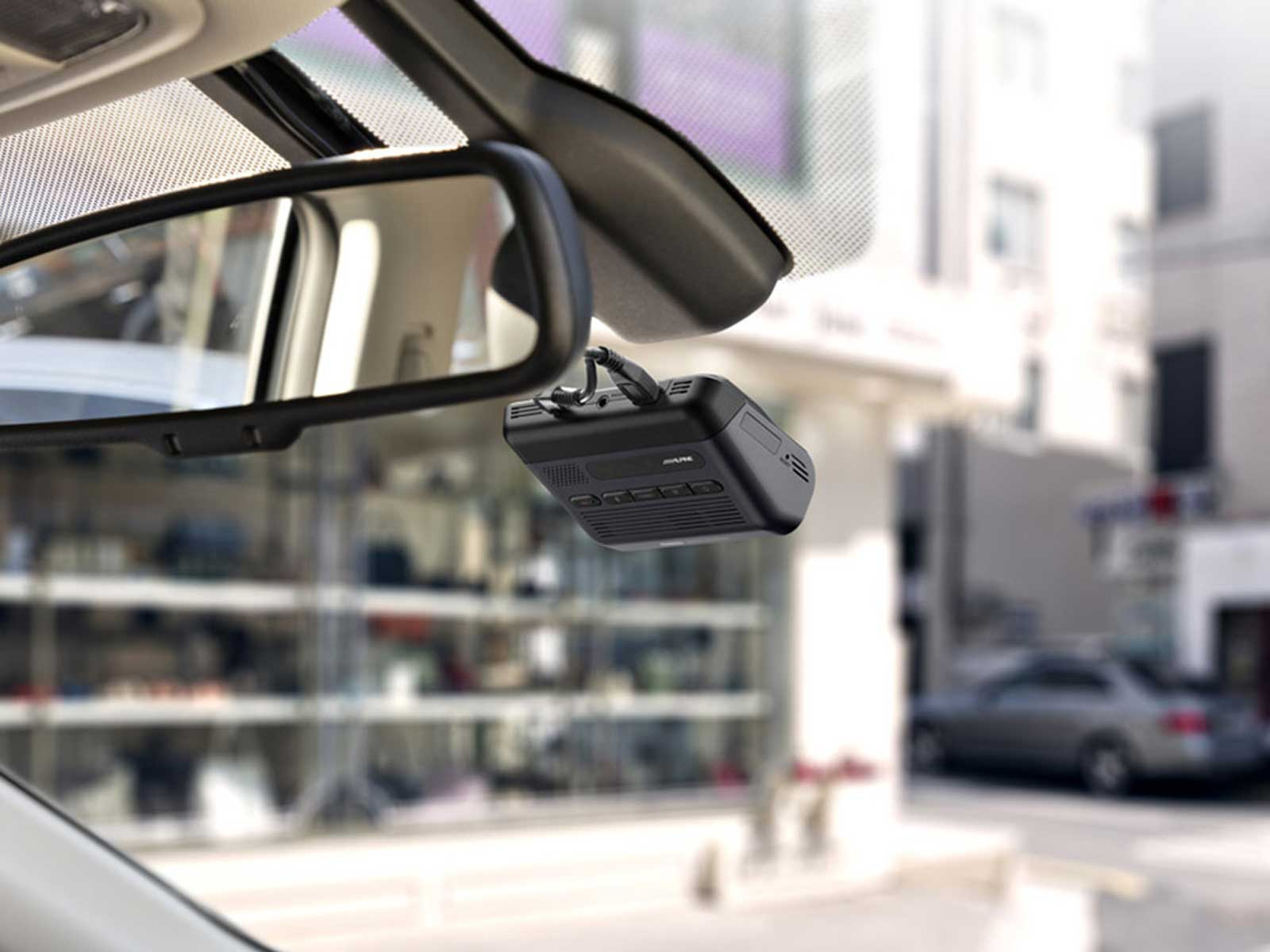 Ein Autointerieur mit einer am Windschutzscheibe montierten Dashcam, die den Rückspiegel und das Äußere zeigt.