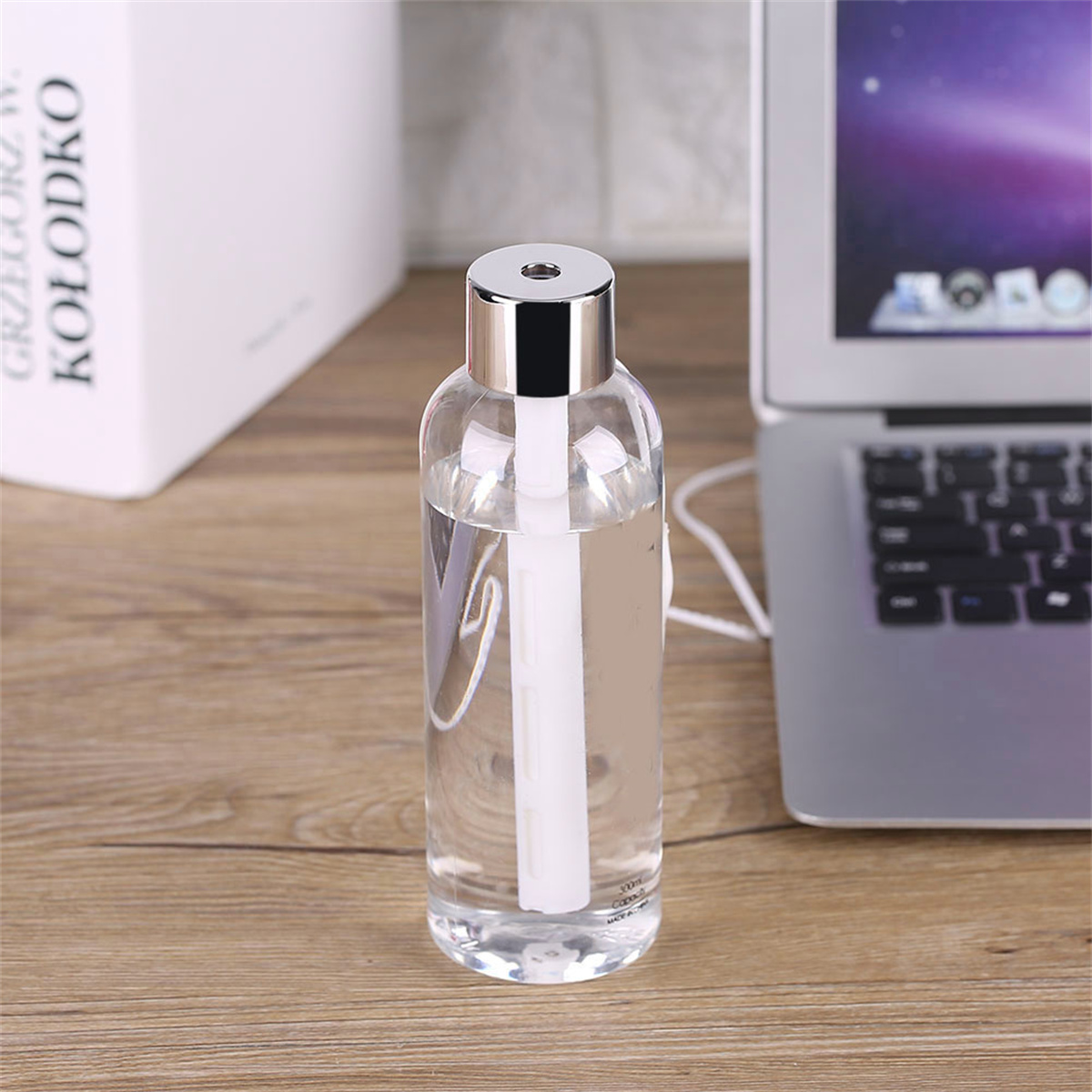 Klare Wasserflasche mit weißem Schlauch, neben Laptop auf Holzschreibtisch. Weiße Box hinten.