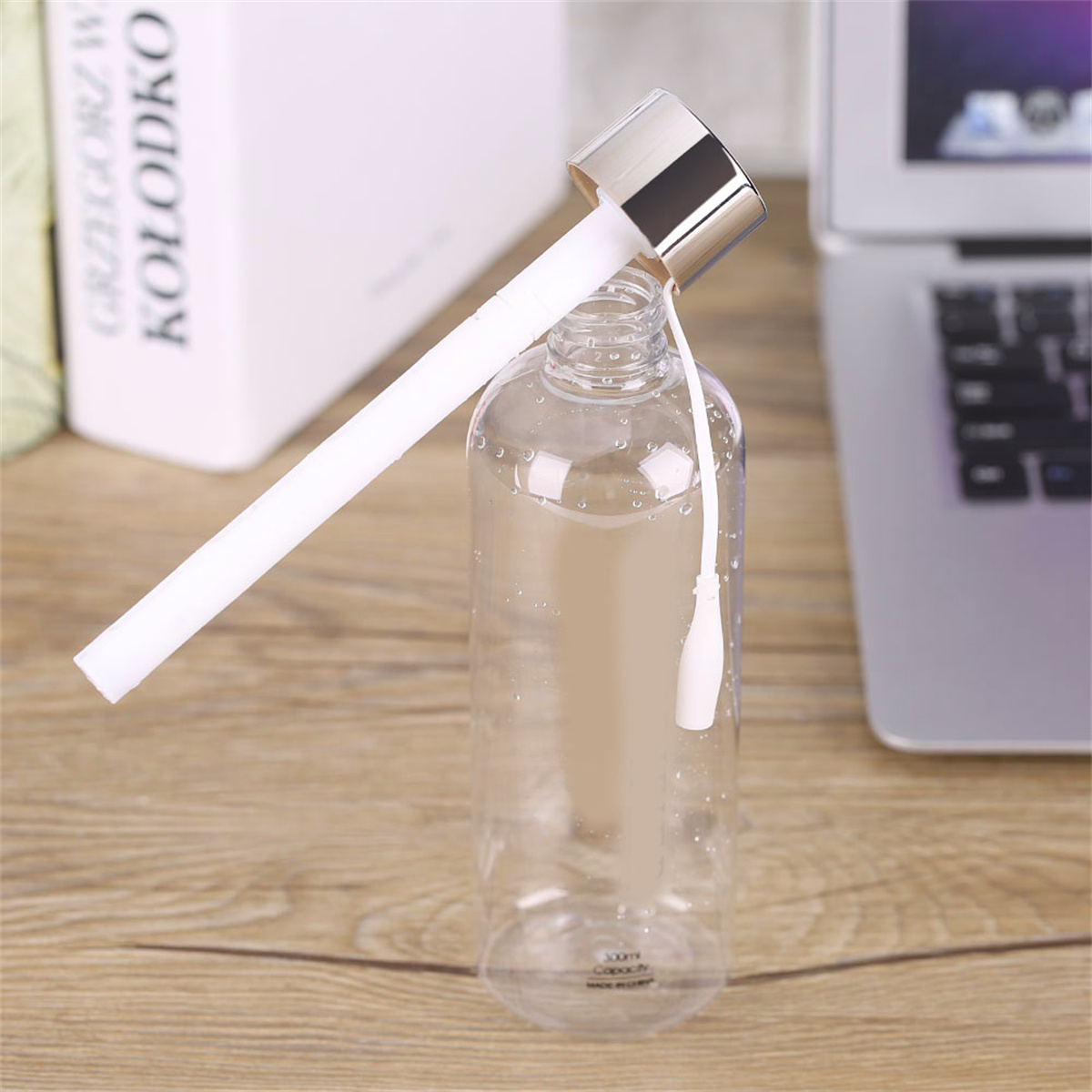 Transparente Wasserflasche mit weißem Deckel und Strohhalm. Daneben sind ein Laptop und Bücher zu sehen.