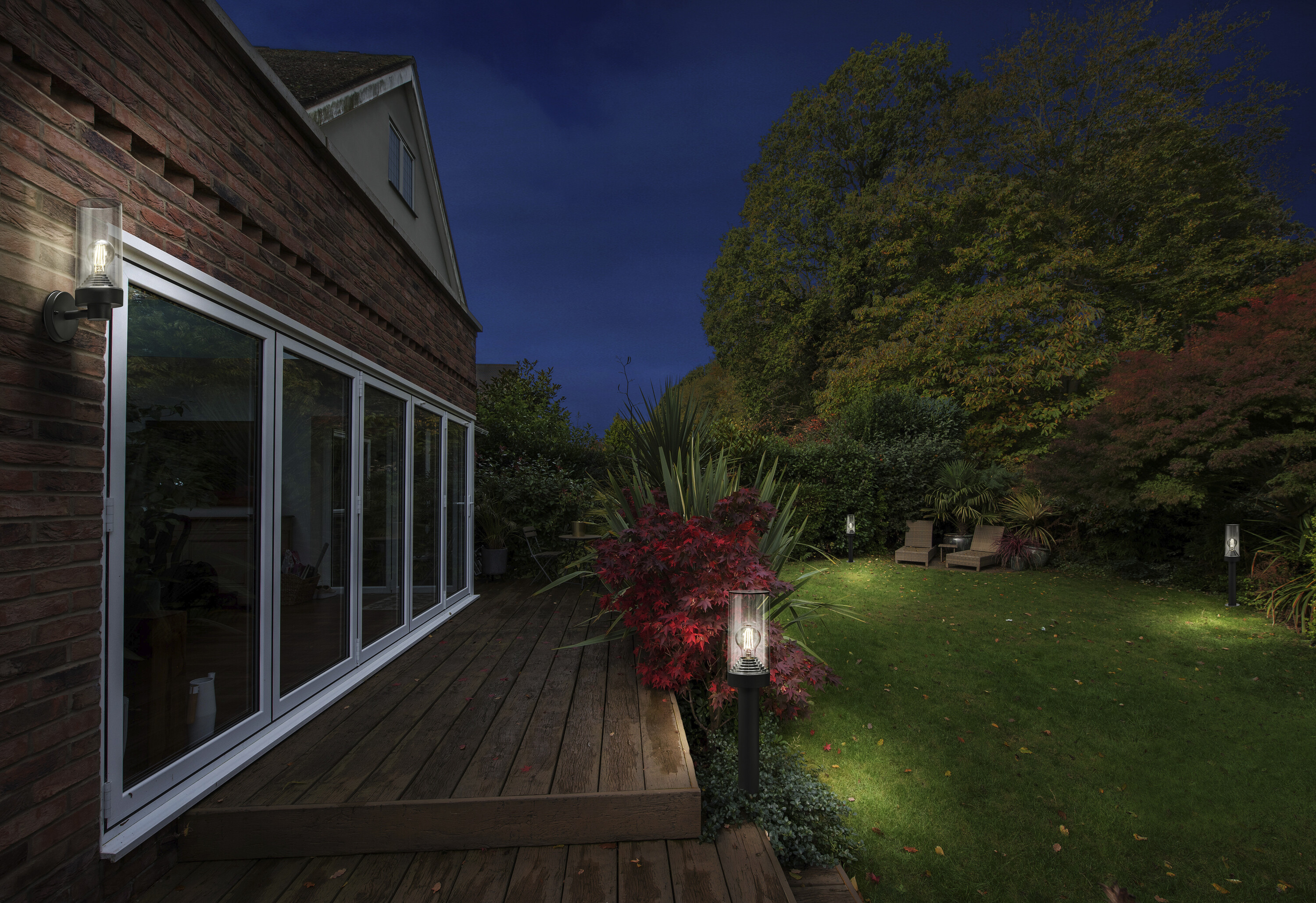 Außenaufnahme bei Nacht. Haus mit Lichtern und Garten mit beleuchteten Pflanzen.