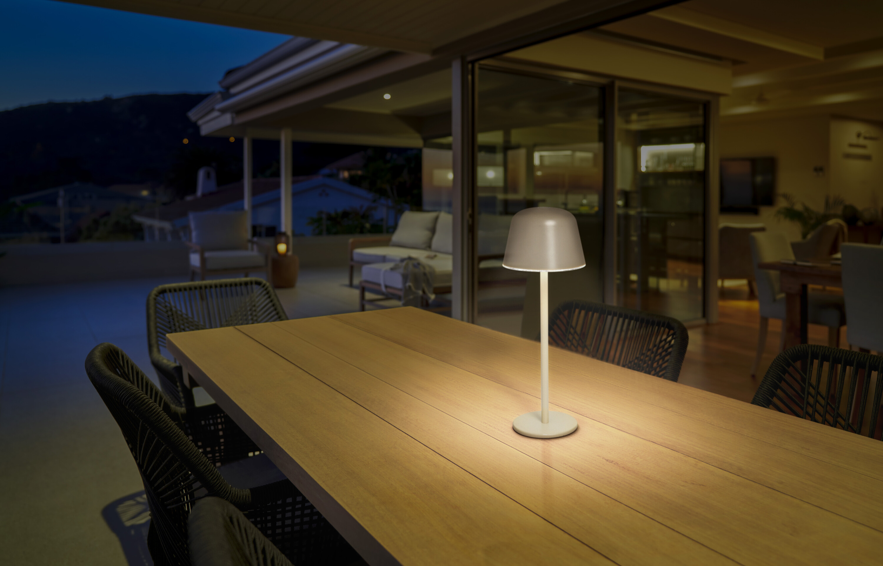 Una lampada da tavolo accesa su un tavolo di legno su un patio di notte.