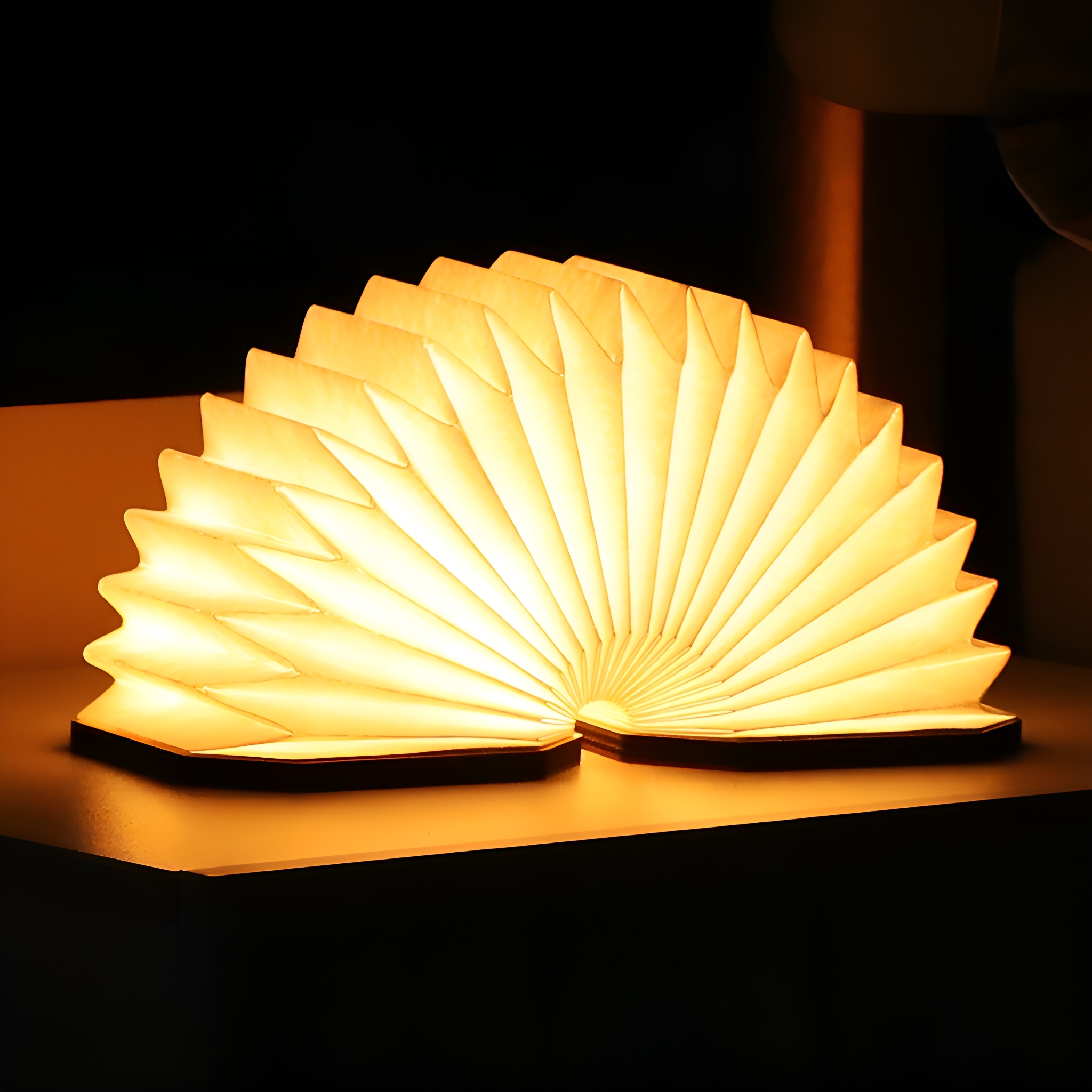 Eine buchförmige LED-Lampe, mit offenen Seiten, die ein warmes, gelbes Licht ausstrahlen.