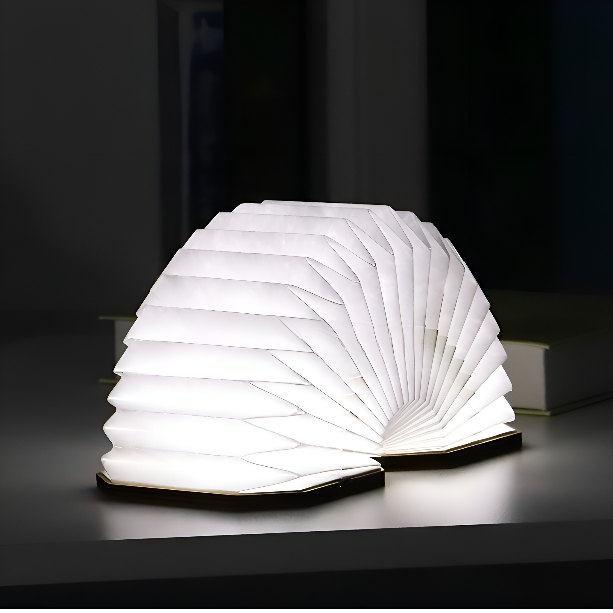 Beleuchtete, offene Buchlampe, weiße Seiten, schwarzer Sockel, auf einem Tisch. Dunkler Hintergrund.