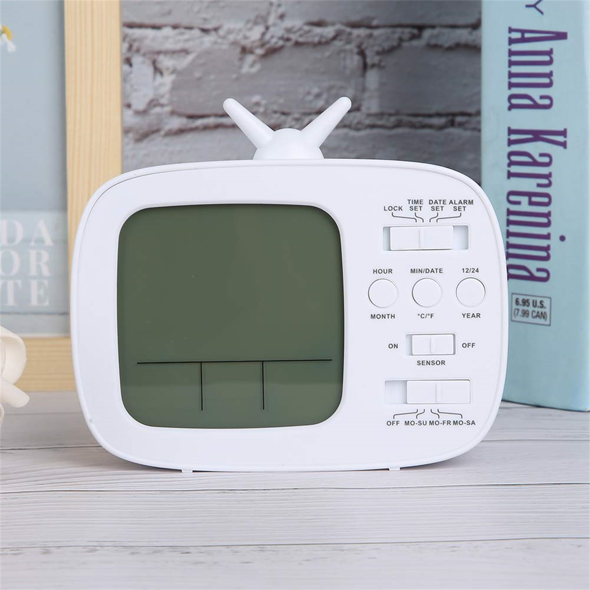 Wecker in Form eines weißen Retro-Fernsehers auf einem Tisch mit Büchern.