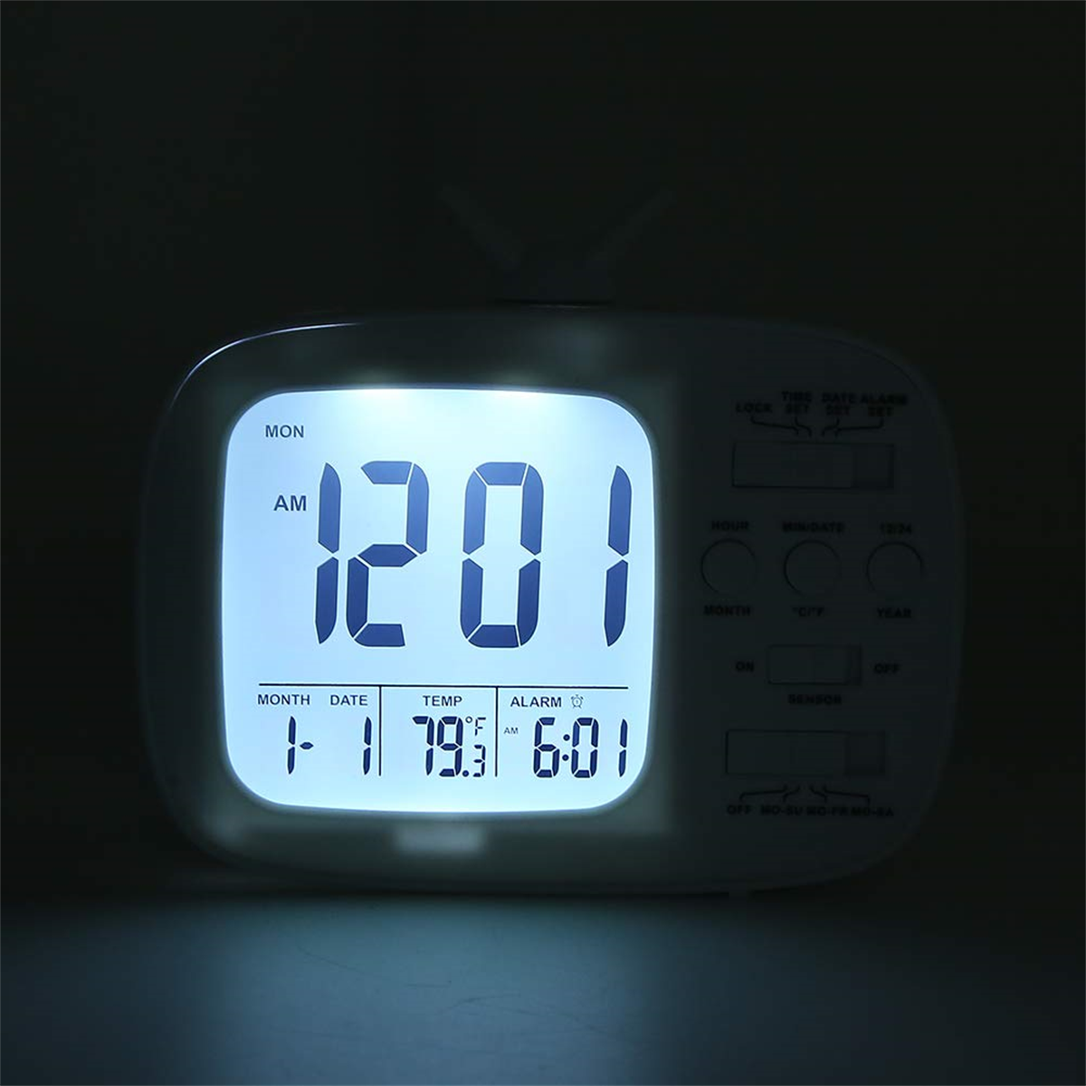 Eine weiße Digitaluhr, die Zeit, Datum und Temperatur anzeigt. Dunkler Hintergrund.