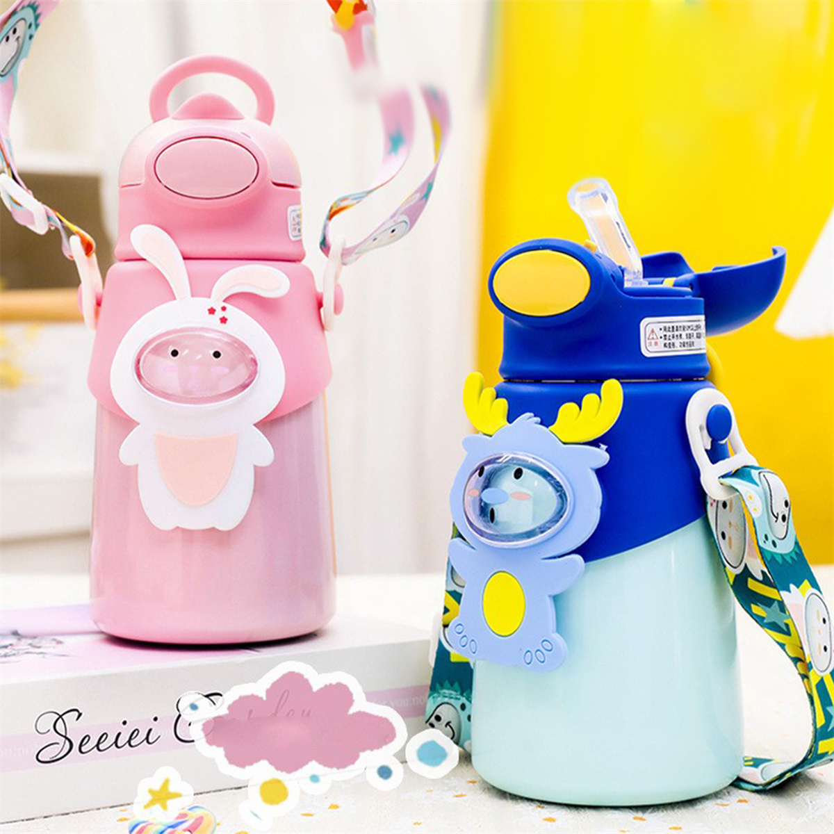 Zwei Kinderwasserflaschen, eine rosa mit einem Hasen und eine blaue mit einem Rentier. Beide haben Riemen.