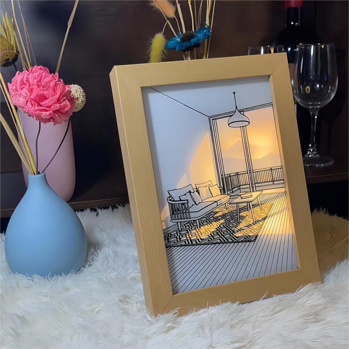 Ein gerahmtes Bild eines skizzierten Zimmers mit Fenster und Sonnenuntergang. Eine Vase und Blumen sind da.