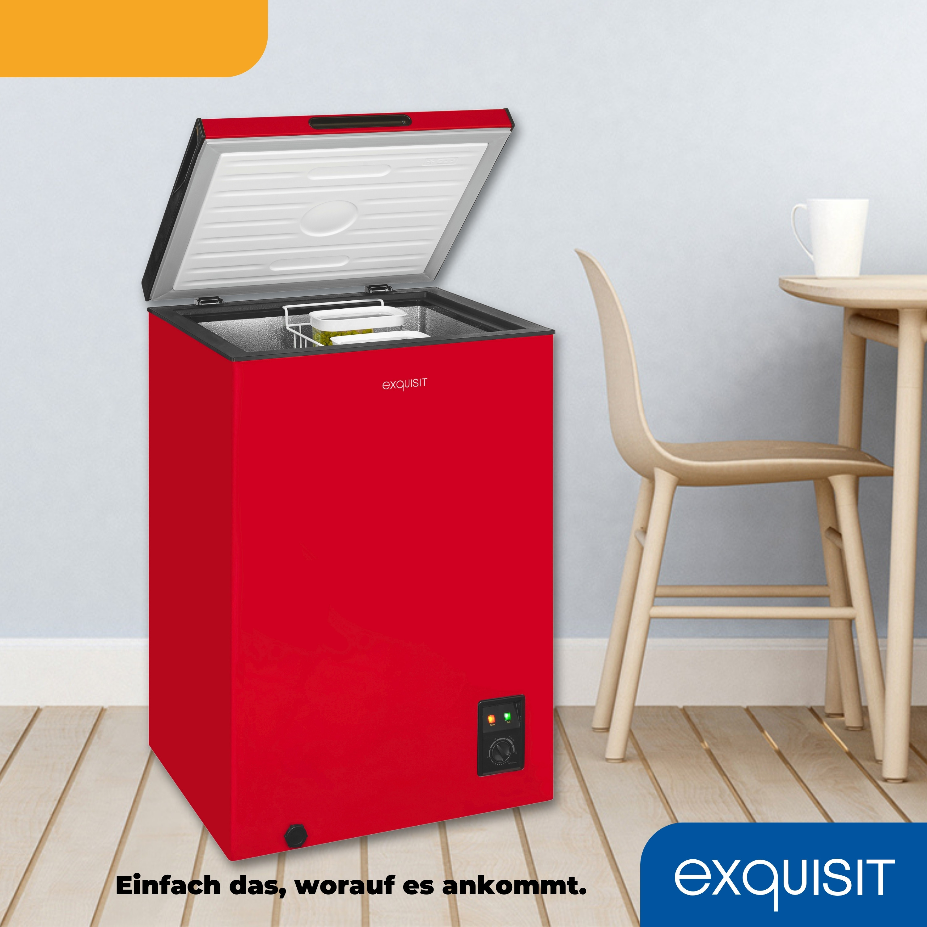 Ein roter Gefrierschrank mit offenem Deckel. Ein Tisch und ein Stuhl sind im Hintergrund. Text 'exquisit'.
