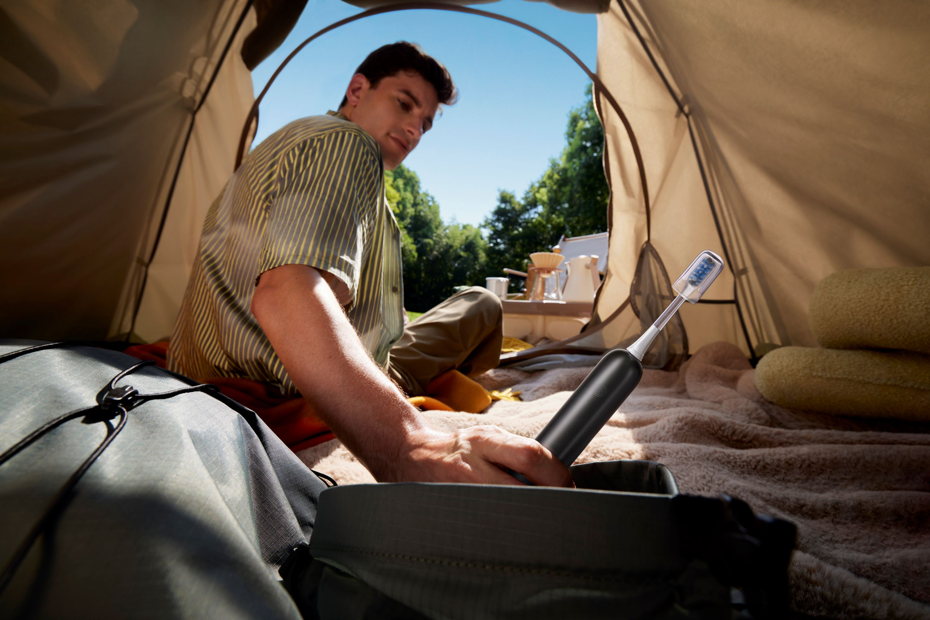 Ein Mann in einem Zelt, der in eine Tasche greift, in der sich eine Zahnbürste befindet. Camping-Szene.