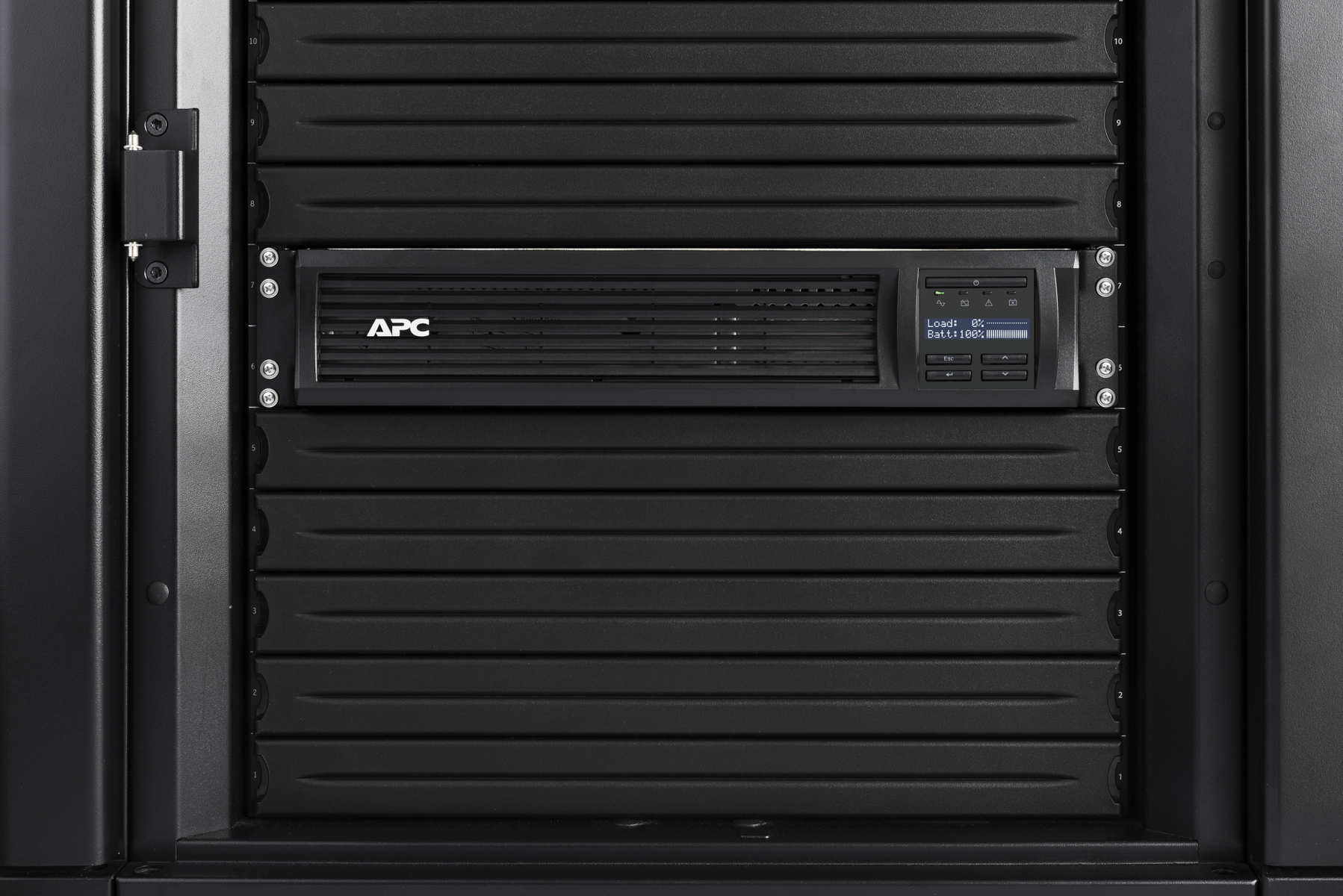 Un rack server nero con un'unità UPS APC nera installata al centro. Lo sfondo è scuro.