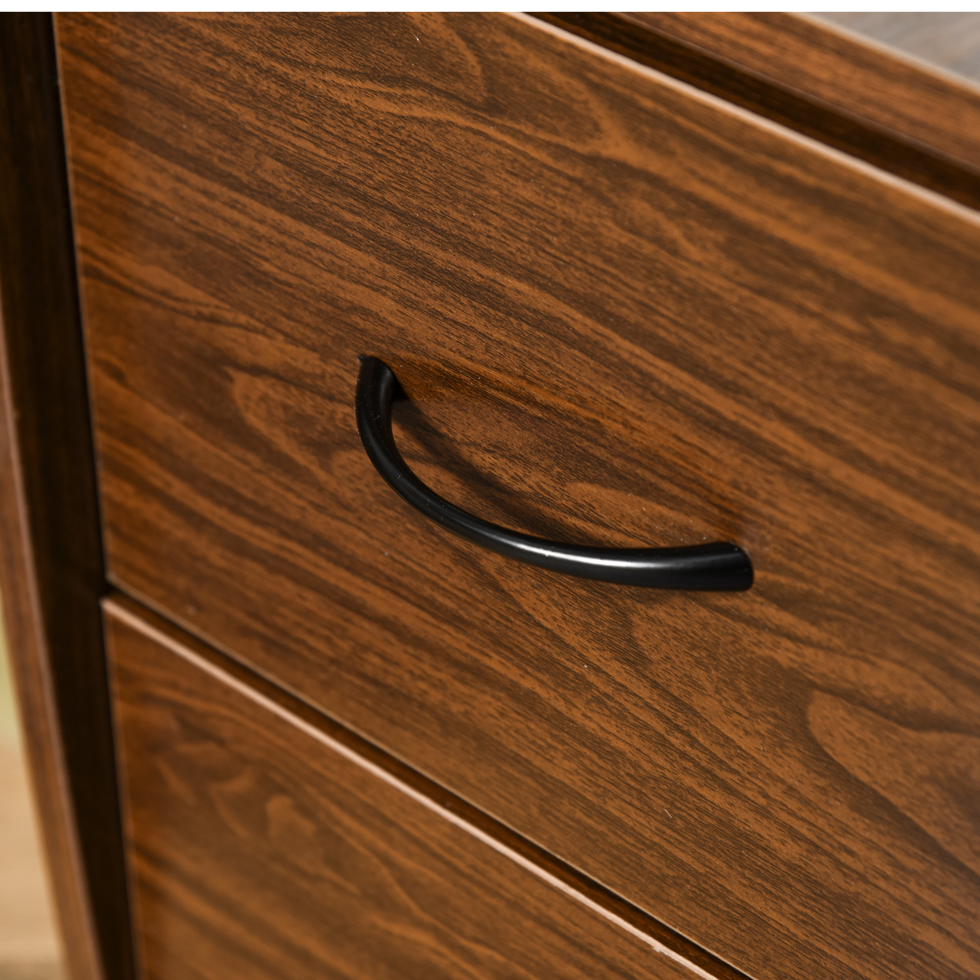 Primo piano di un cassetto in legno con maniglia nera. Venatura del legno visibile.