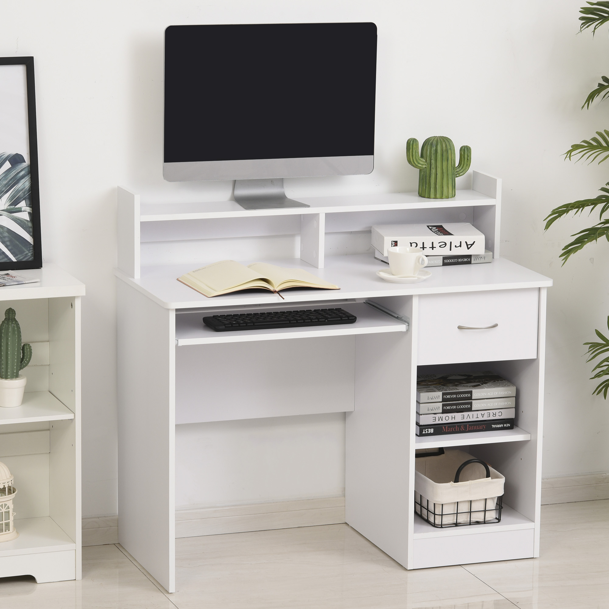Scrivania bianca con computer, vassoio per tastiera e vani portaoggetti. Libri, cactus e decorazioni.