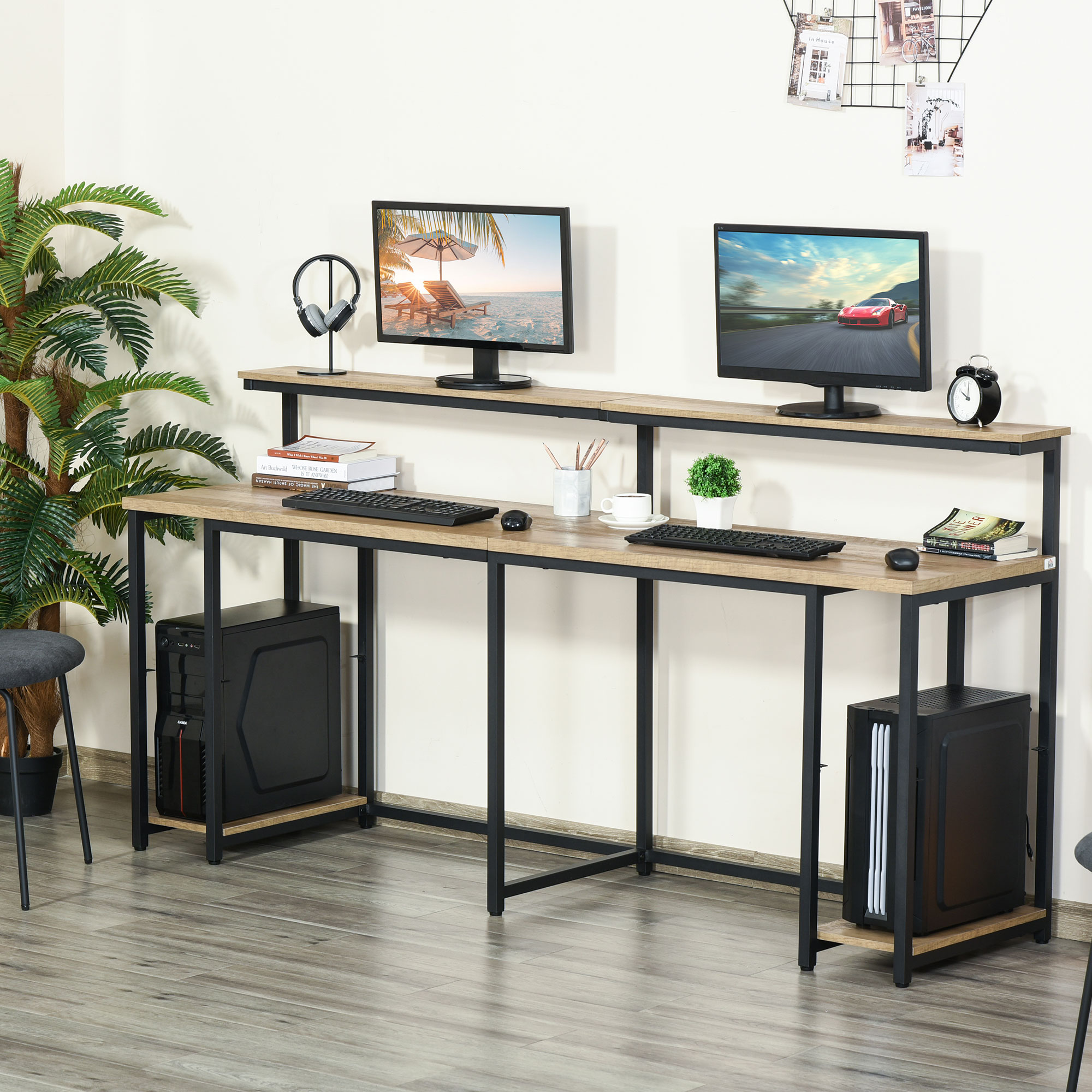 Due computer su una scrivania con cornici nere e telaio in metallo, circondati da accessori e decorazioni.