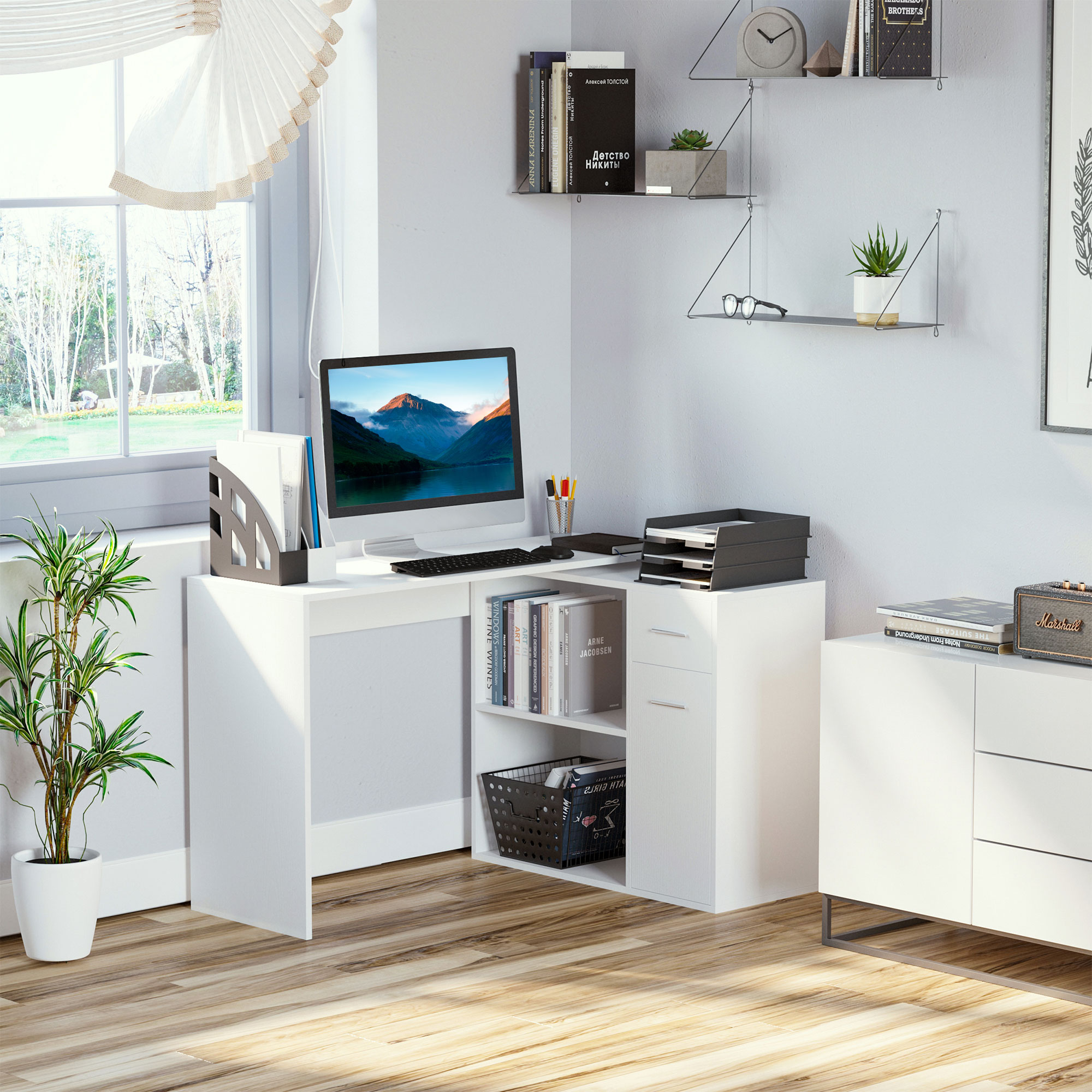 Scrivania angolare bianca con monitor, tastiera e accessori, vicino a finestra e mobile.
