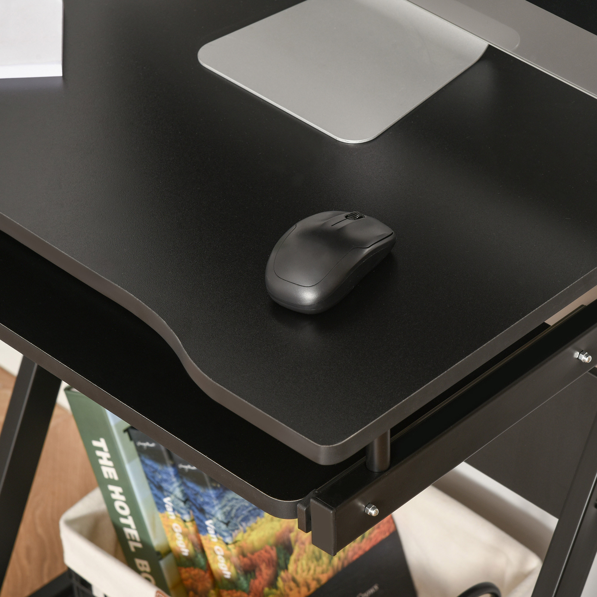 Un primo piano mostra una scrivania nera con un mouse. La superficie è nera e ha un vassoio per tastiera.