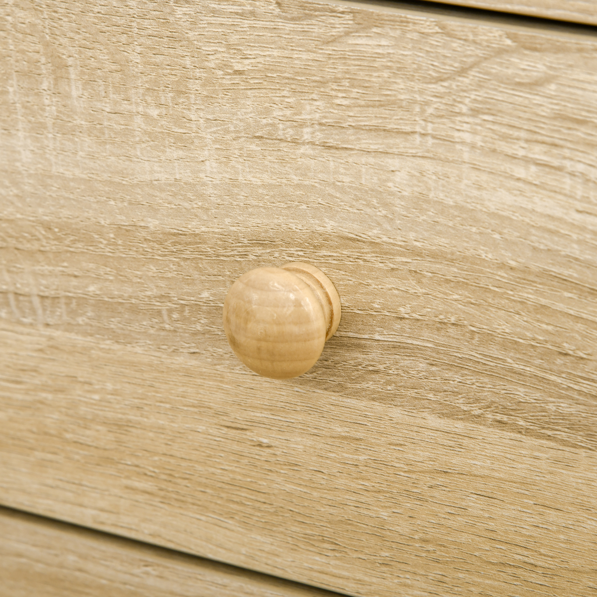 Primo piano di un pomello del cassetto in legno. La manopola è rotonda e di colore chiaro.