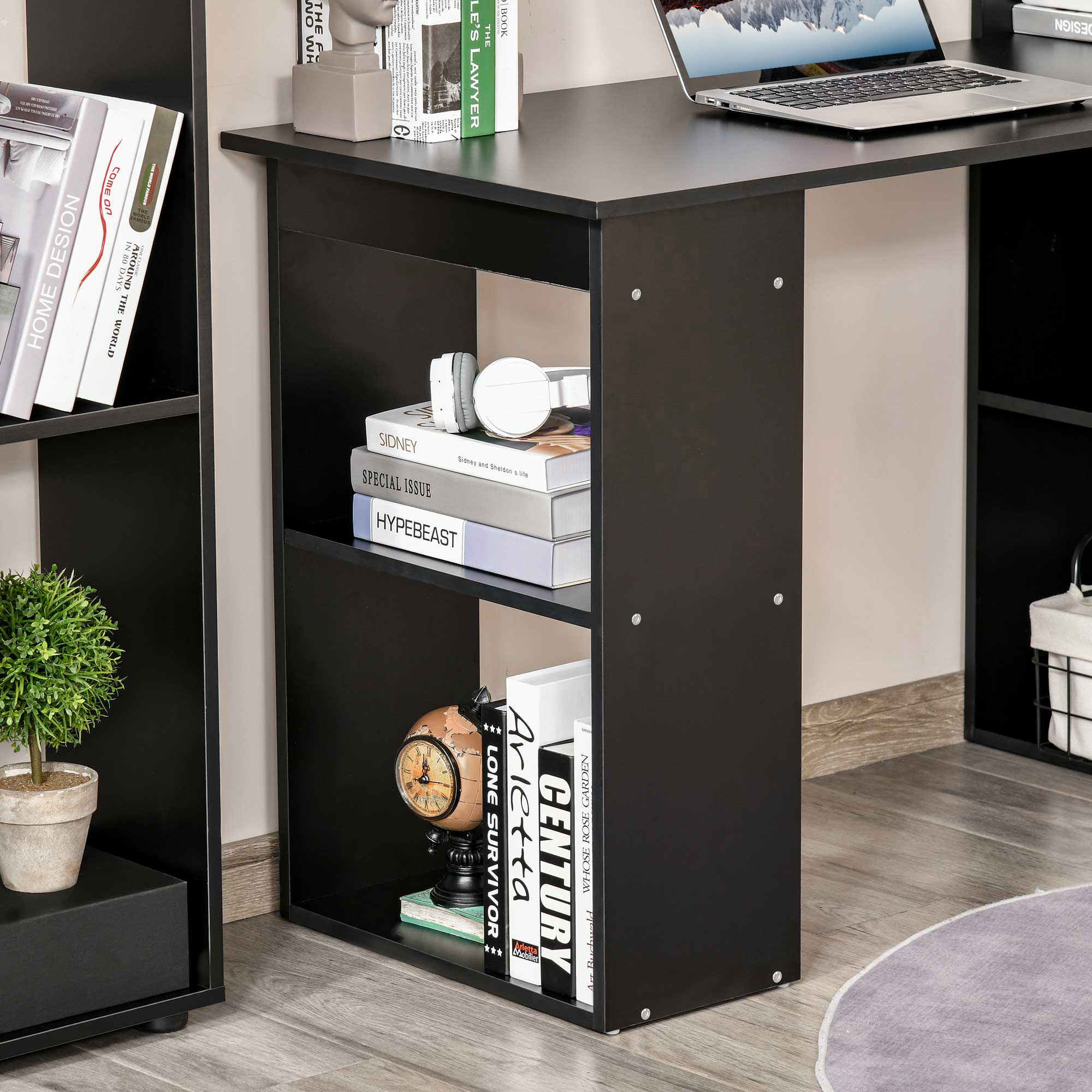 Scrivania nera con mensole e libri. Sono presenti cuffie e altoparlanti bianchi.