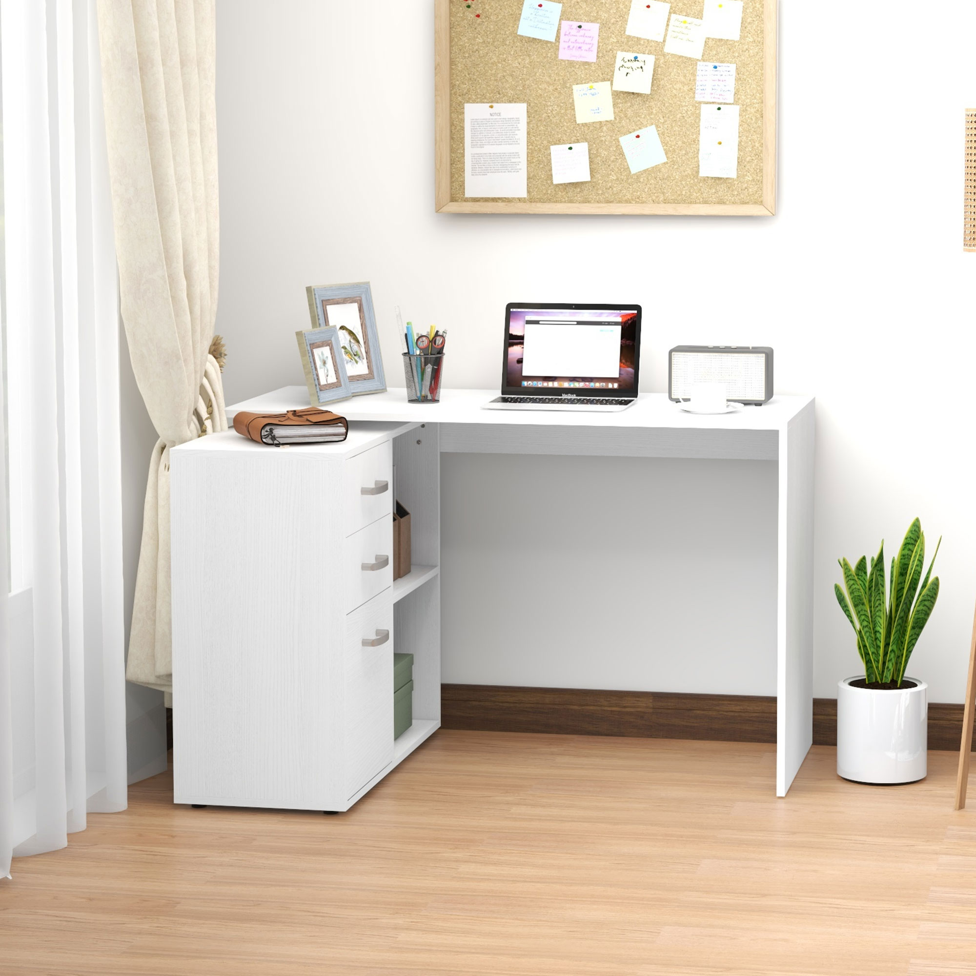 Scrivania bianca a L con cassetti, bacheca e pianta. Include un laptop e oggetti decorativi.