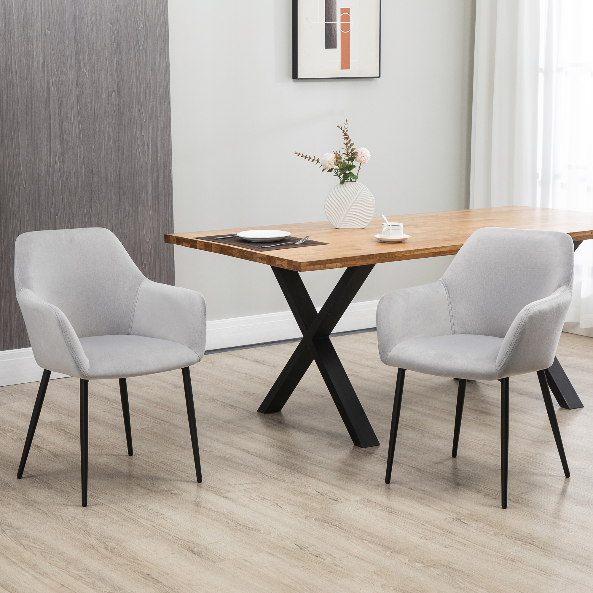 Due sedie grigie con gambe nere di fronte a un tavolo da pranzo con base a forma di X.