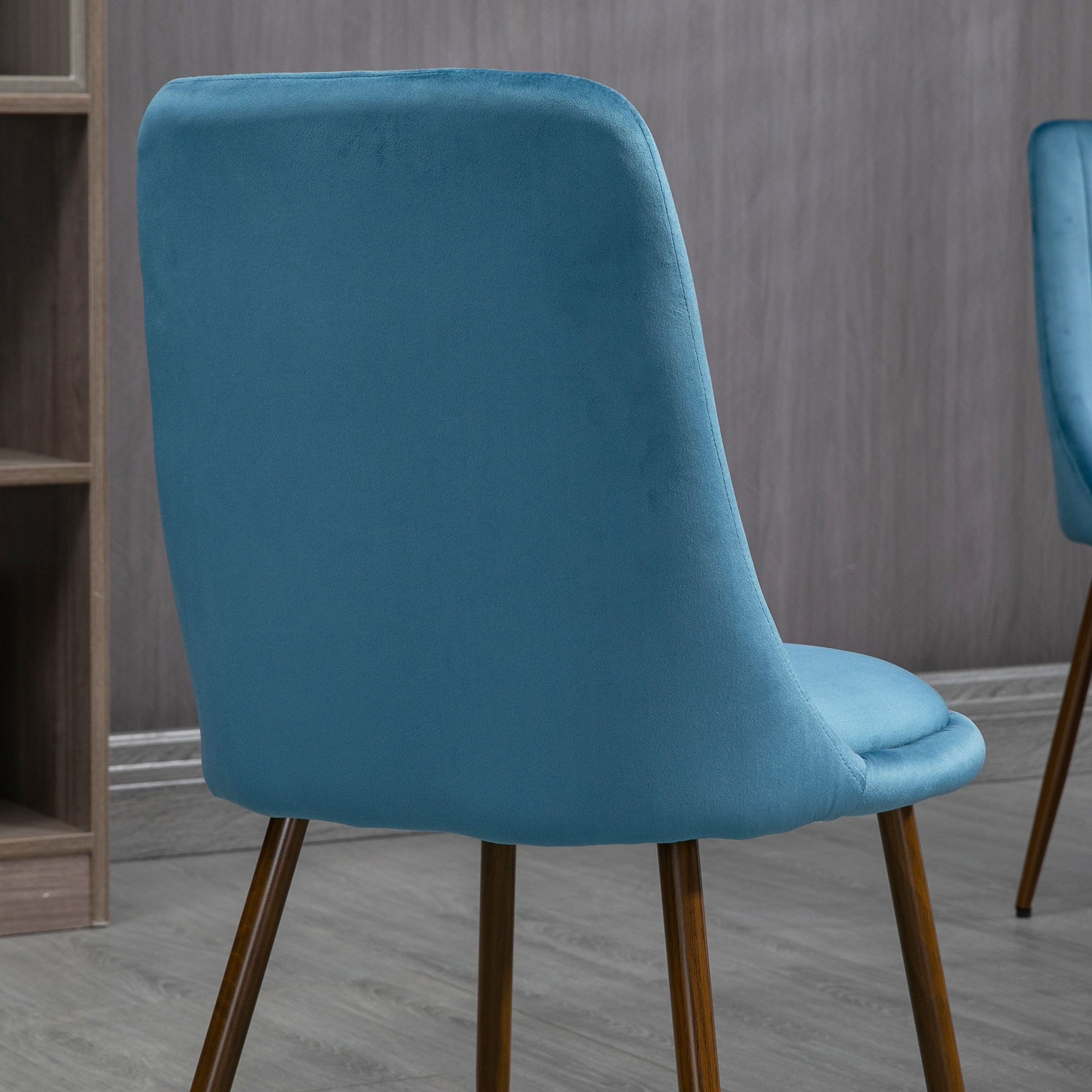 Primo piano dello schienale di una sedia blu. La sedia ha uno schienale curvo e gambe in legno.