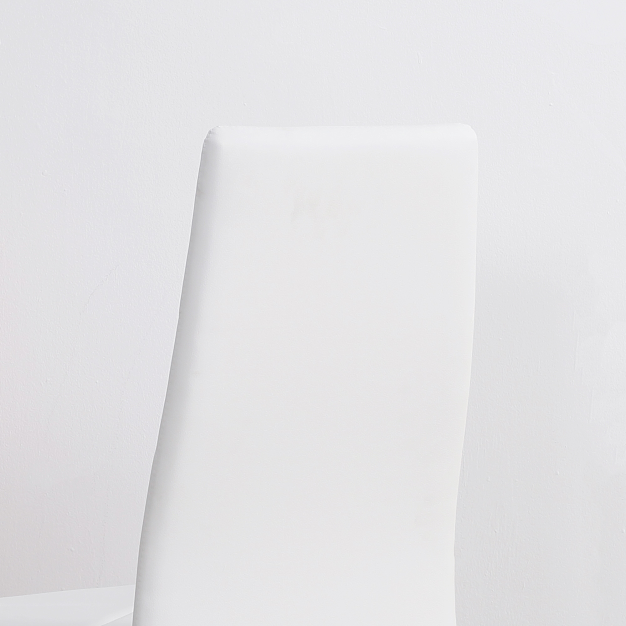 Primo piano dello schienale di una sedia bianca su sfondo bianco. La sedia è elegante.
