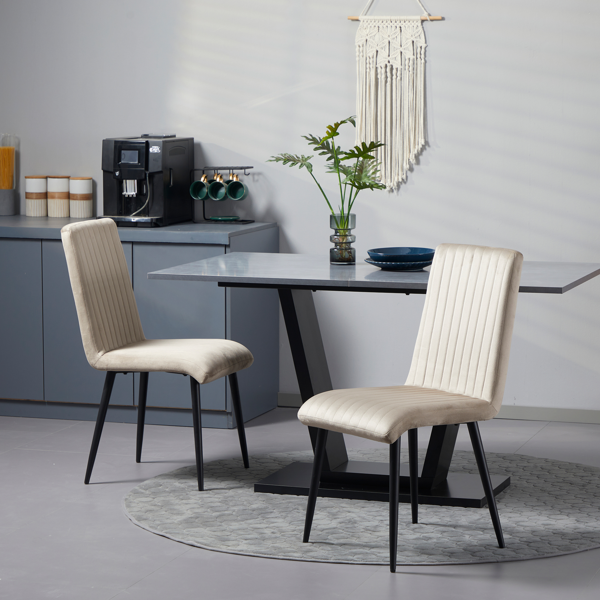Due sedie beige con gambe nere vicino a un tavolo in una cucina moderna.