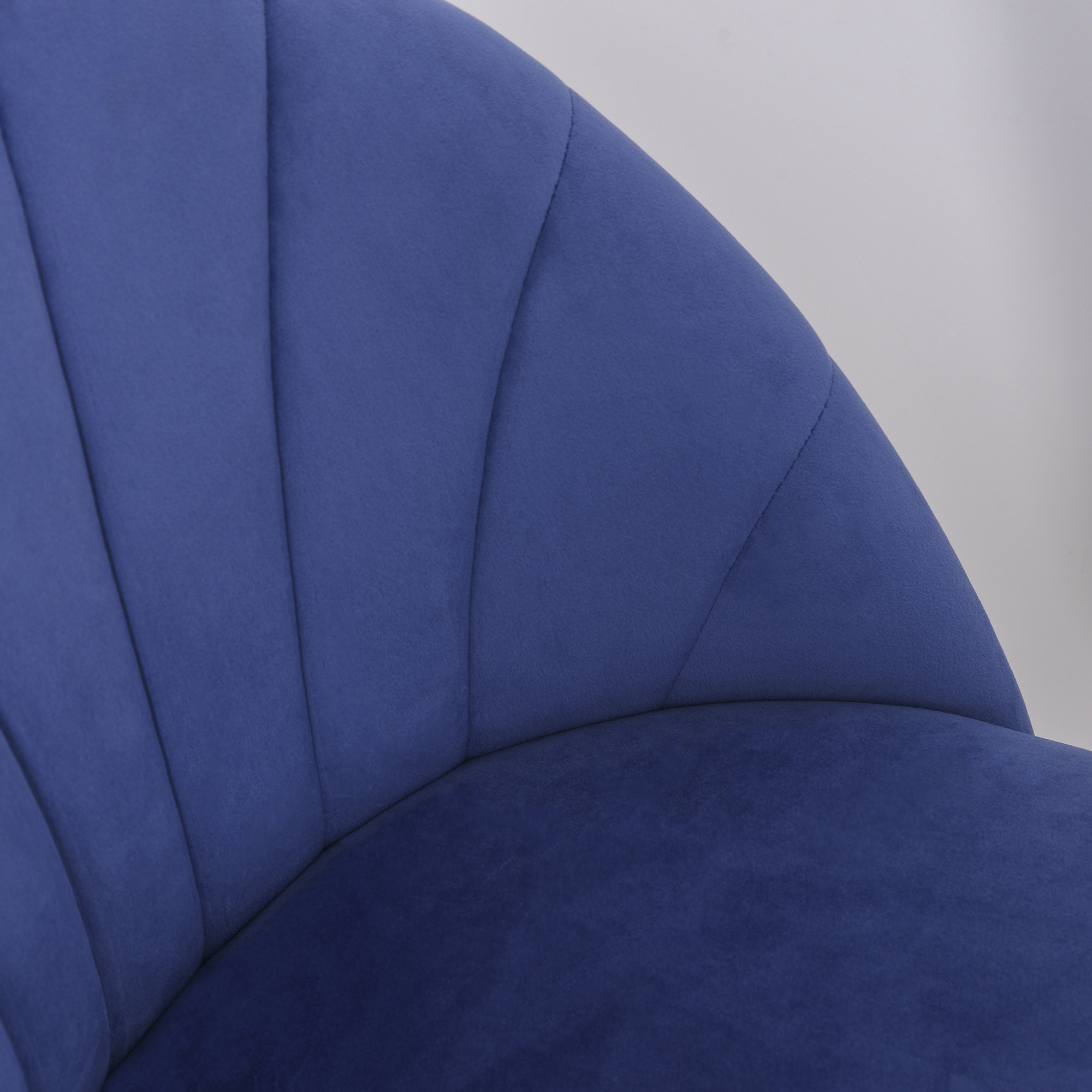 Primo piano di una sedia in velluto blu. La sedia ha un design curvo e scanalato.
