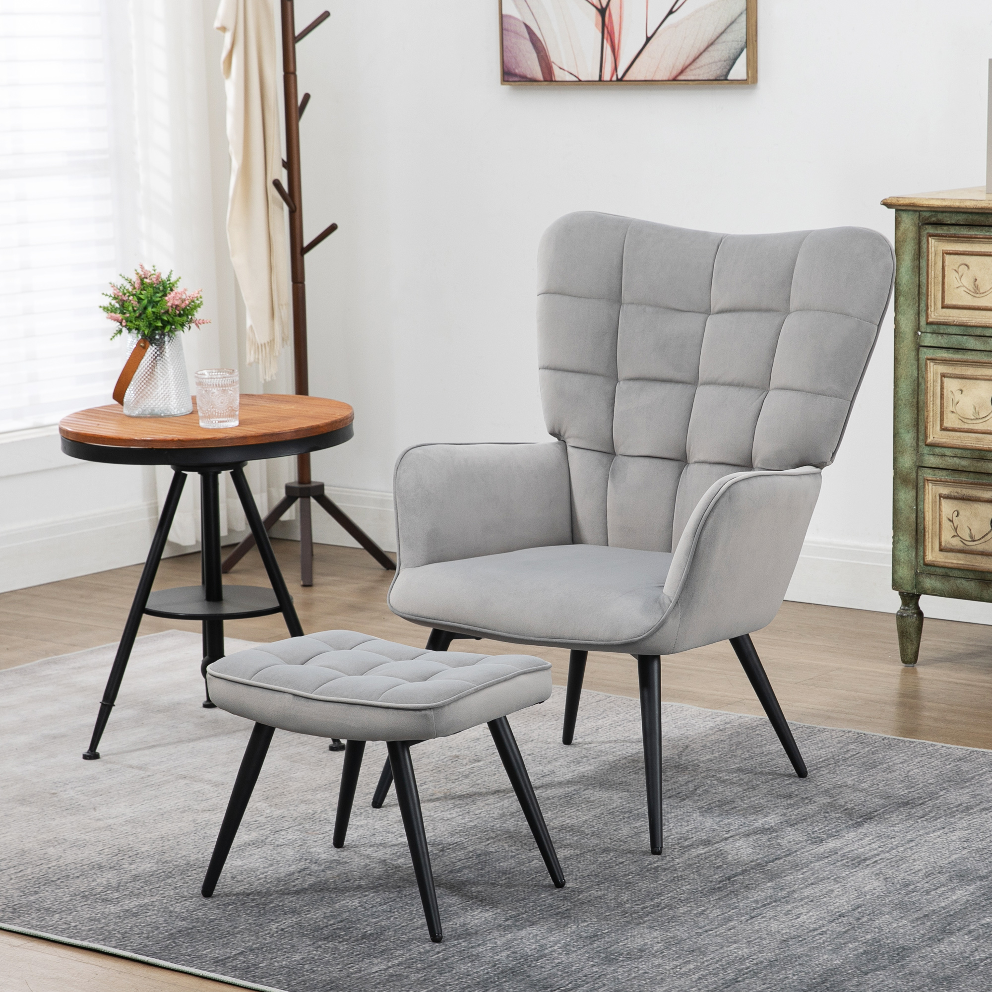 Grauer Sessel und Hocker, kleiner Tisch mit Blumen und ein Beistellschrank.