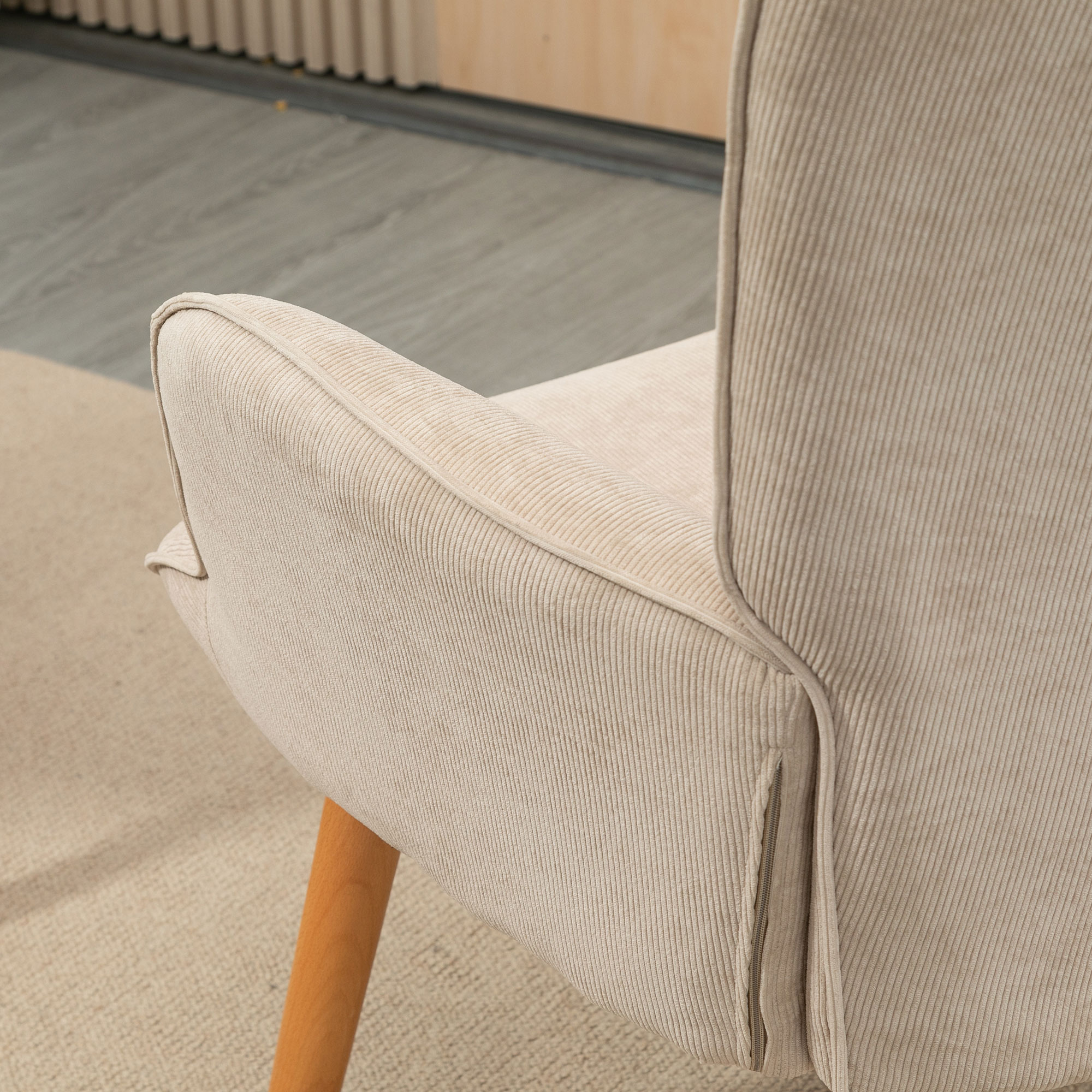 Primo piano di una sedia in velluto a coste beige con gambe in legno.