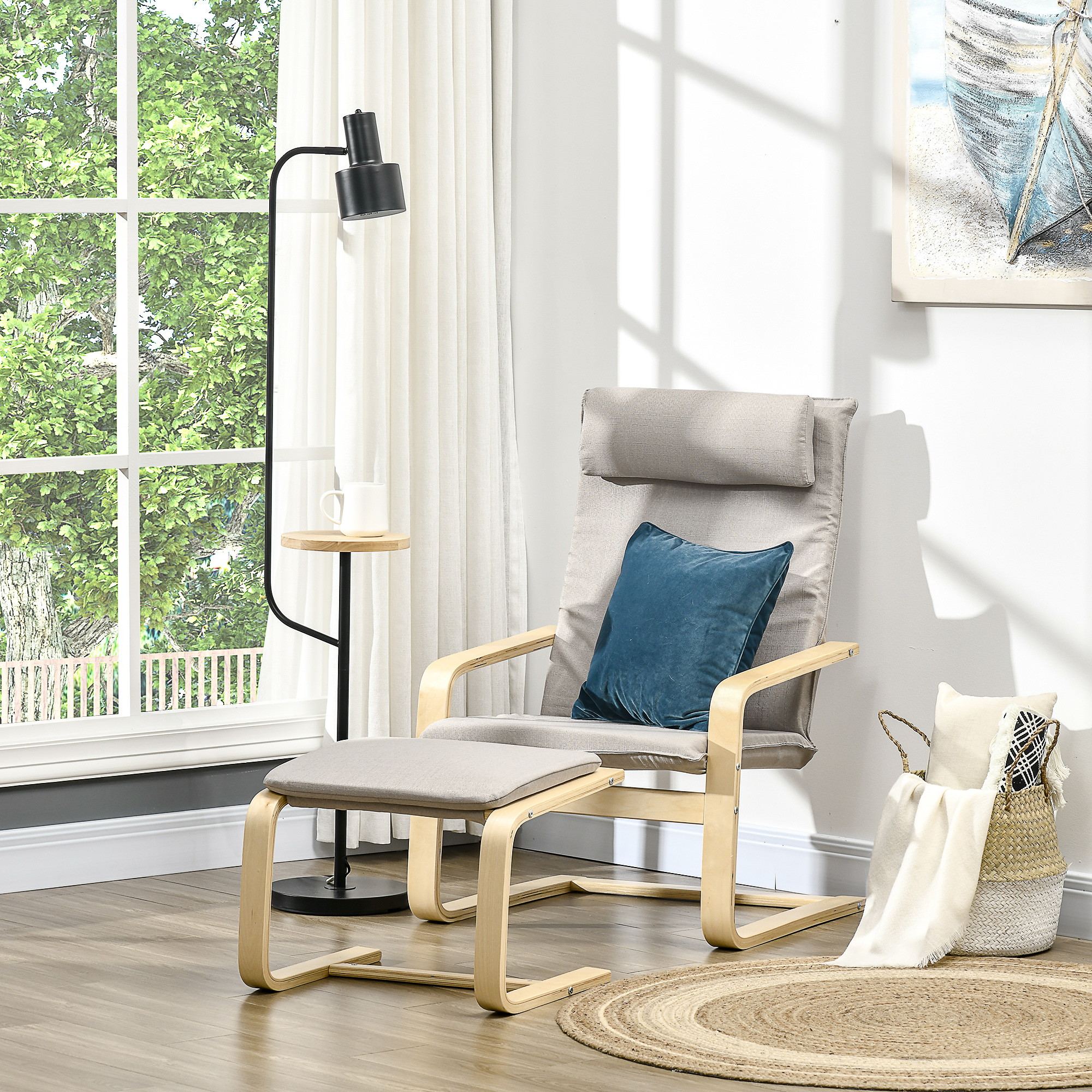 Una sedia grigio chiaro con pouf, una lampada e un tavolino con tazza e decorazioni vicino a una finestra.