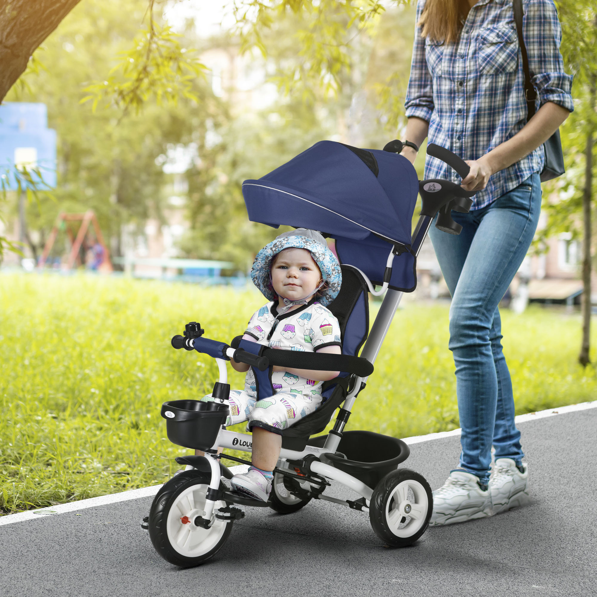 Un bambino in triciclo spinto da una donna su un sentiero lastricato in un parco.