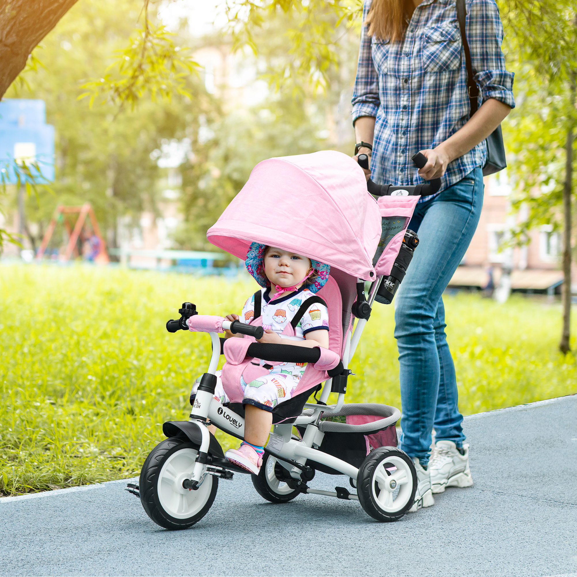 Una donna spinge un triciclo rosa con un bambino seduto. Sono su un sentiero.