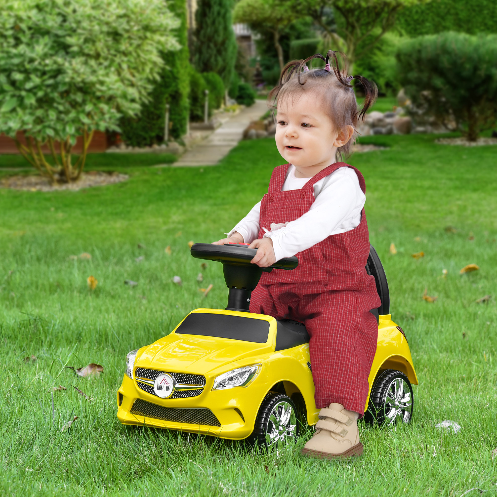 Un bambino guida un'auto giocattolo gialla su un prato verde.