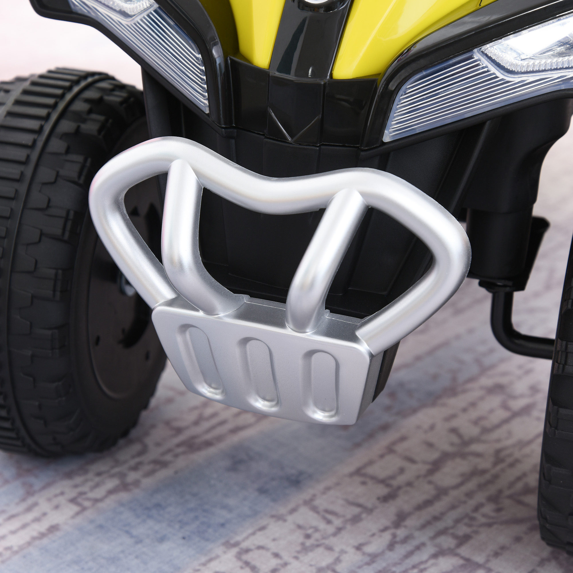 Primo piano della parte anteriore di un ATV giocattolo giallo e nero, che mostra paraurti e fari.